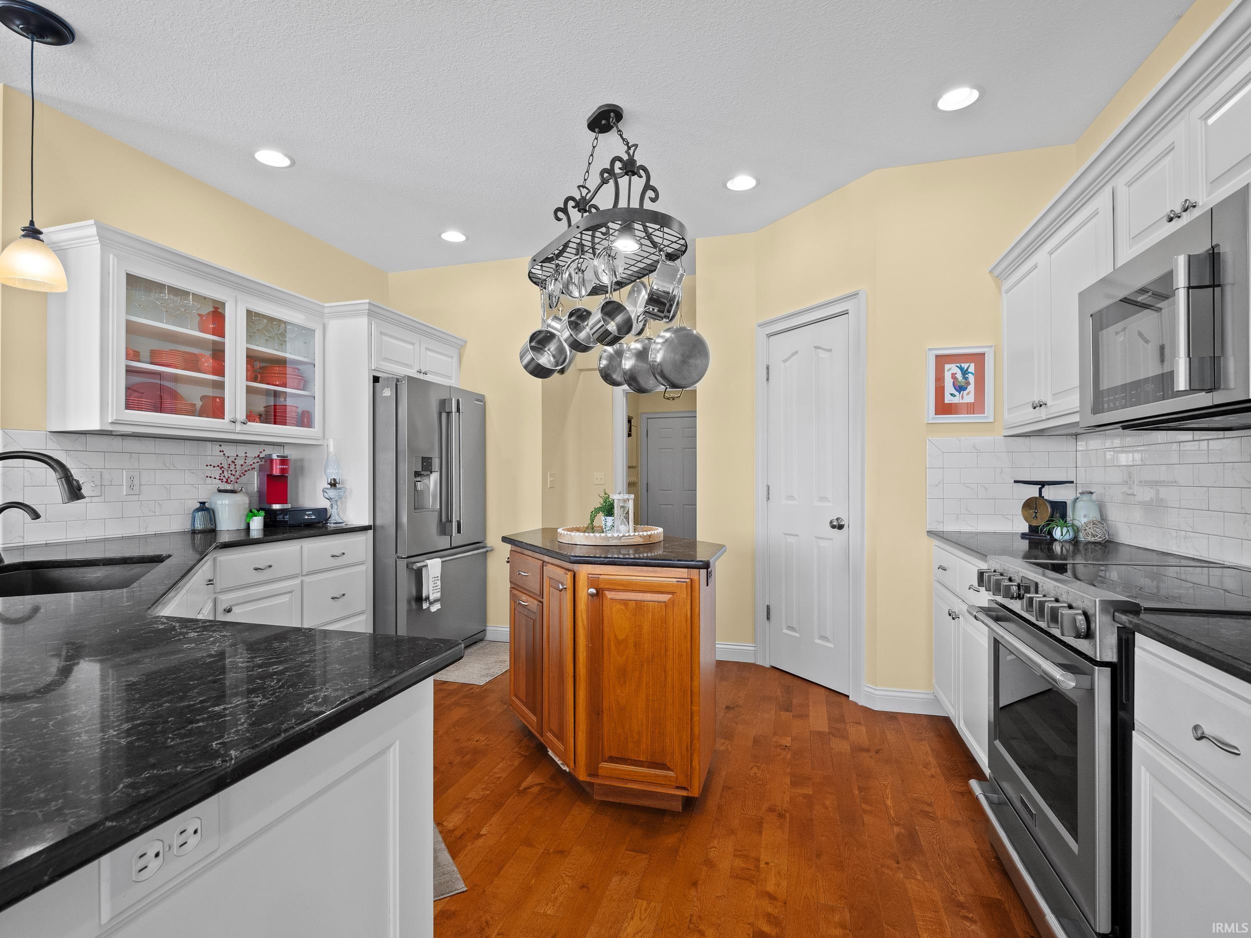 Kitchen featuring backsplash, appliances with stainless steel finishes, white cabinets, and recessed lighting