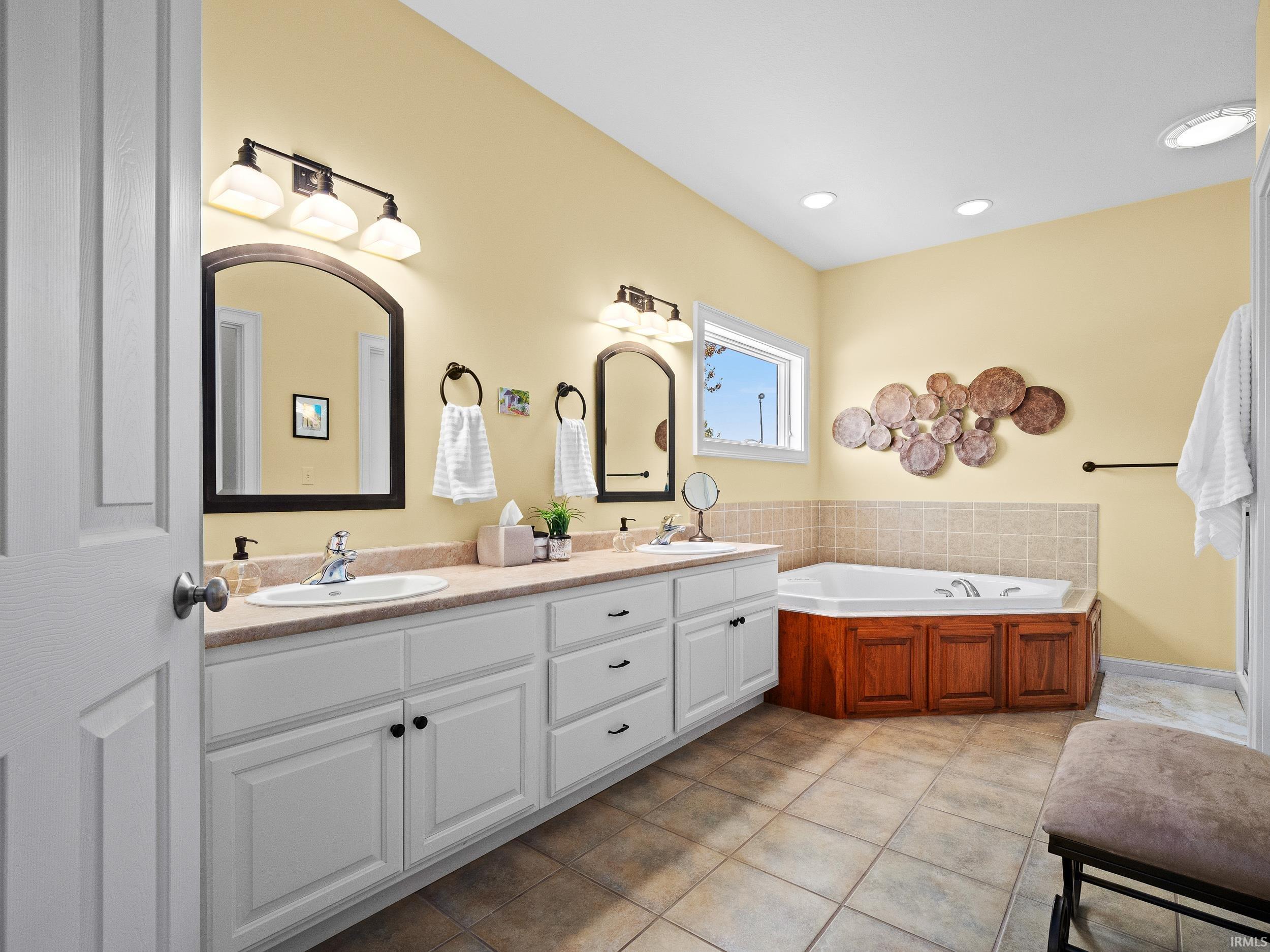 Bathroom featuring double vanity, a bath, and light tile patterned flooring