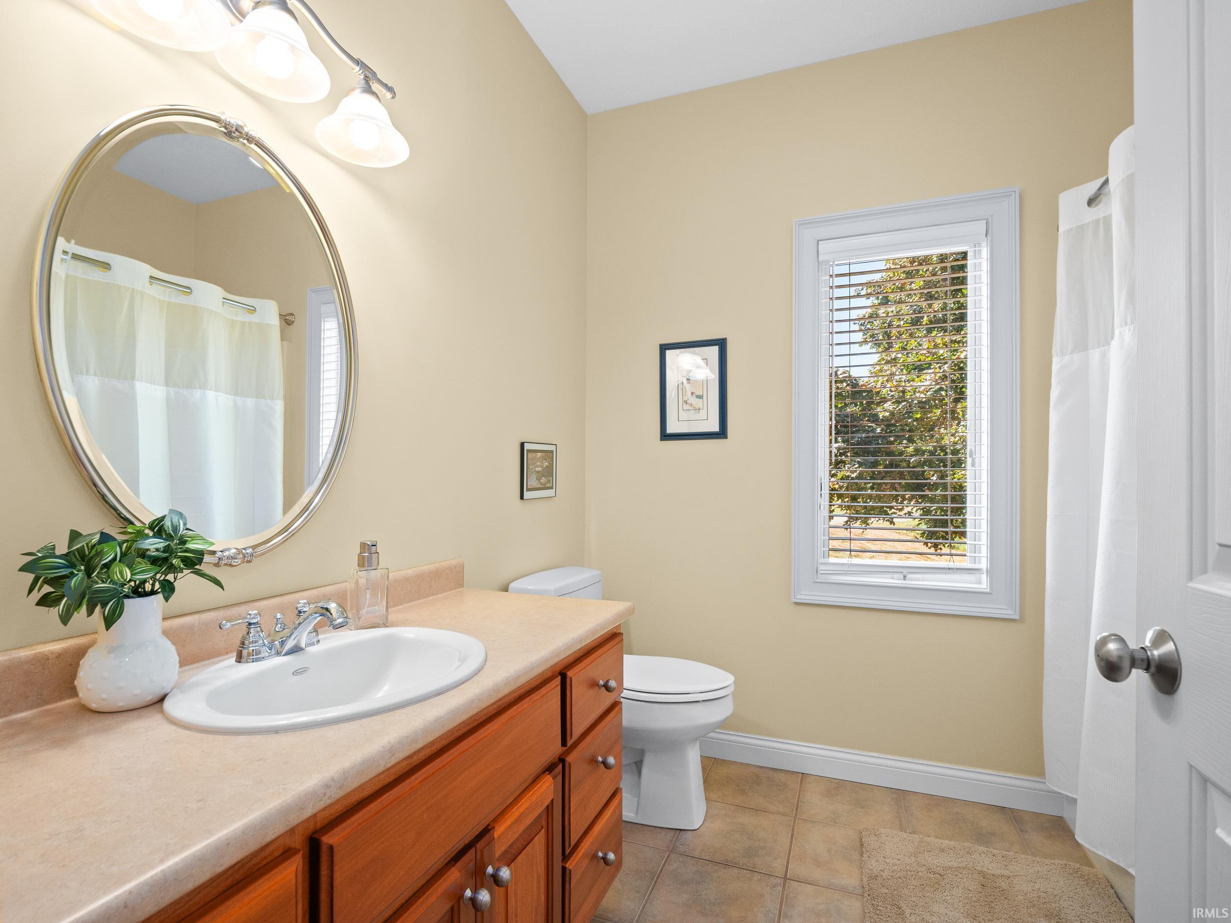 Full bathroom with a shower with curtain, vanity, and light tile patterned flooring