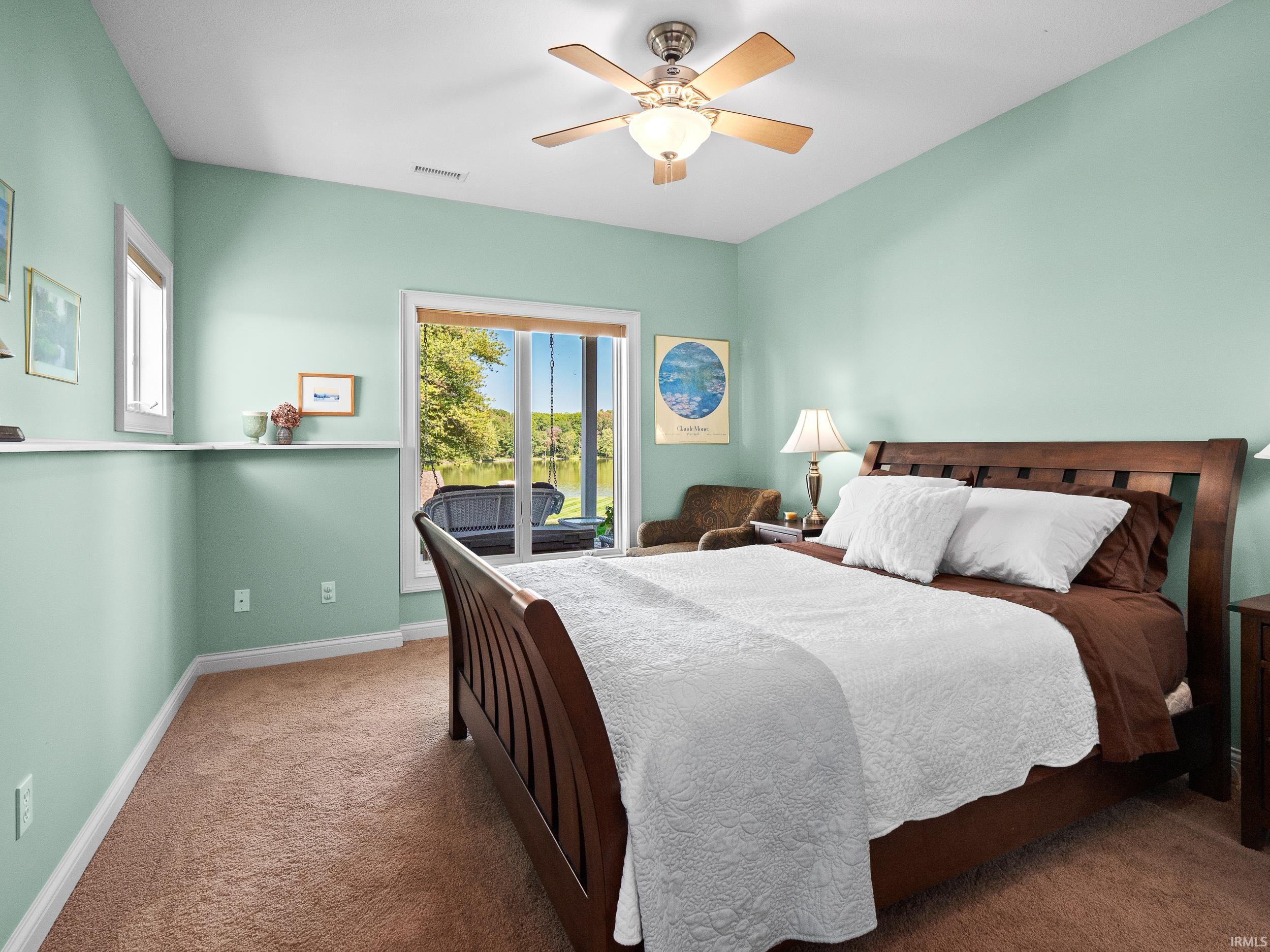 Carpeted bedroom with a ceiling fan and access to exterior