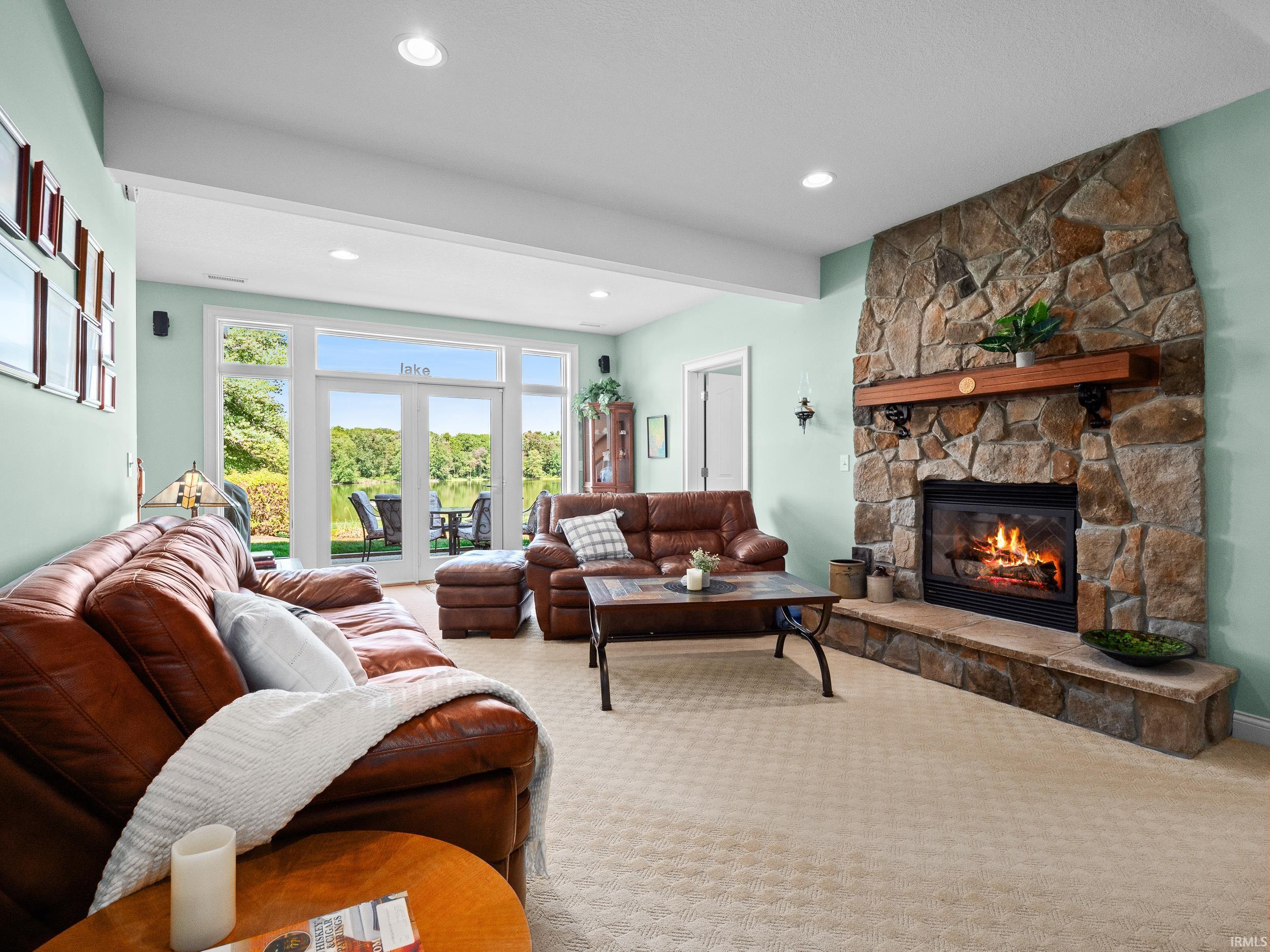 Carpeted living room with a fireplace, recessed lighting, and french doors