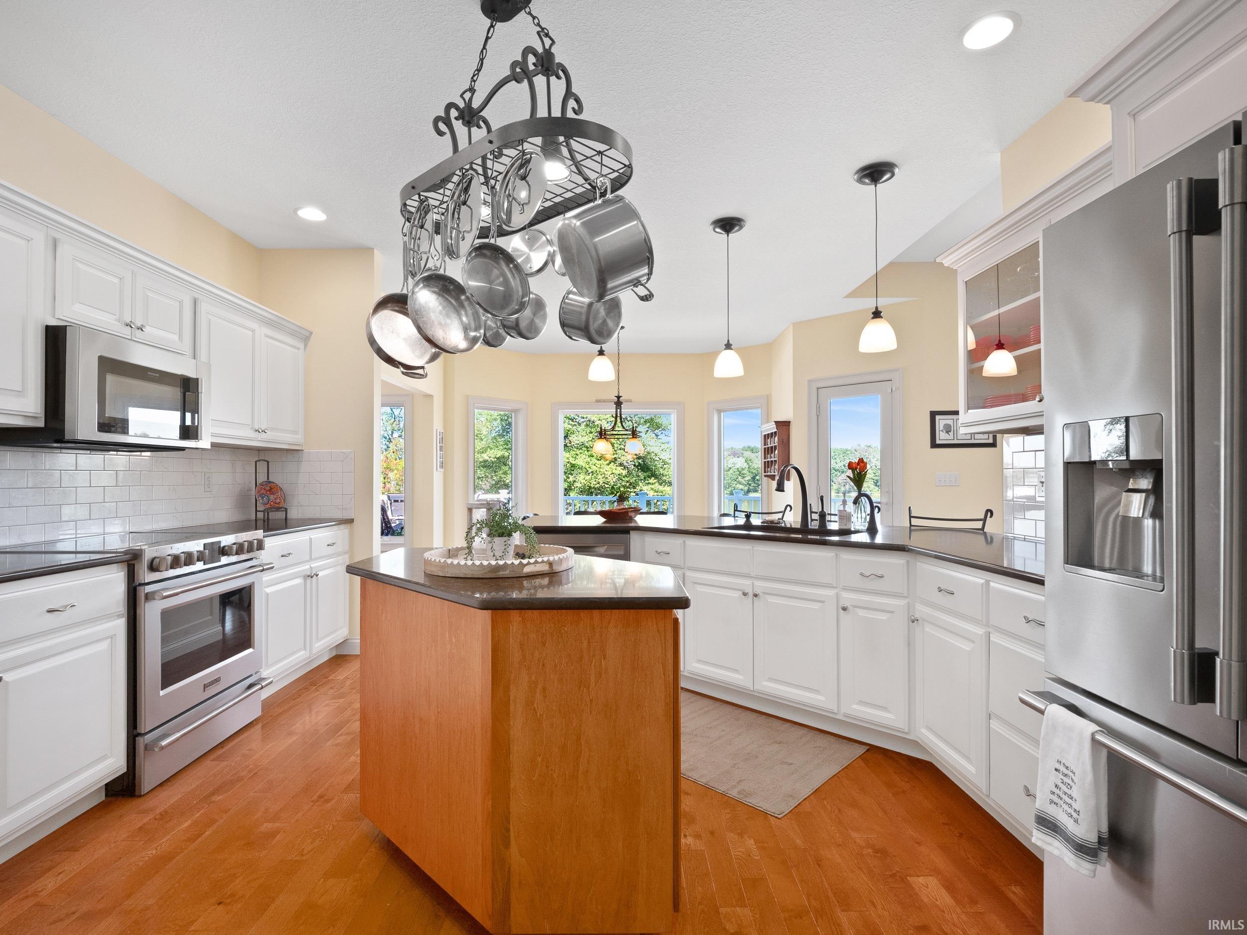 Kitchen featuring white cabinetry, appliances with stainless steel finishes, a peninsula, a center island, and recessed lighting