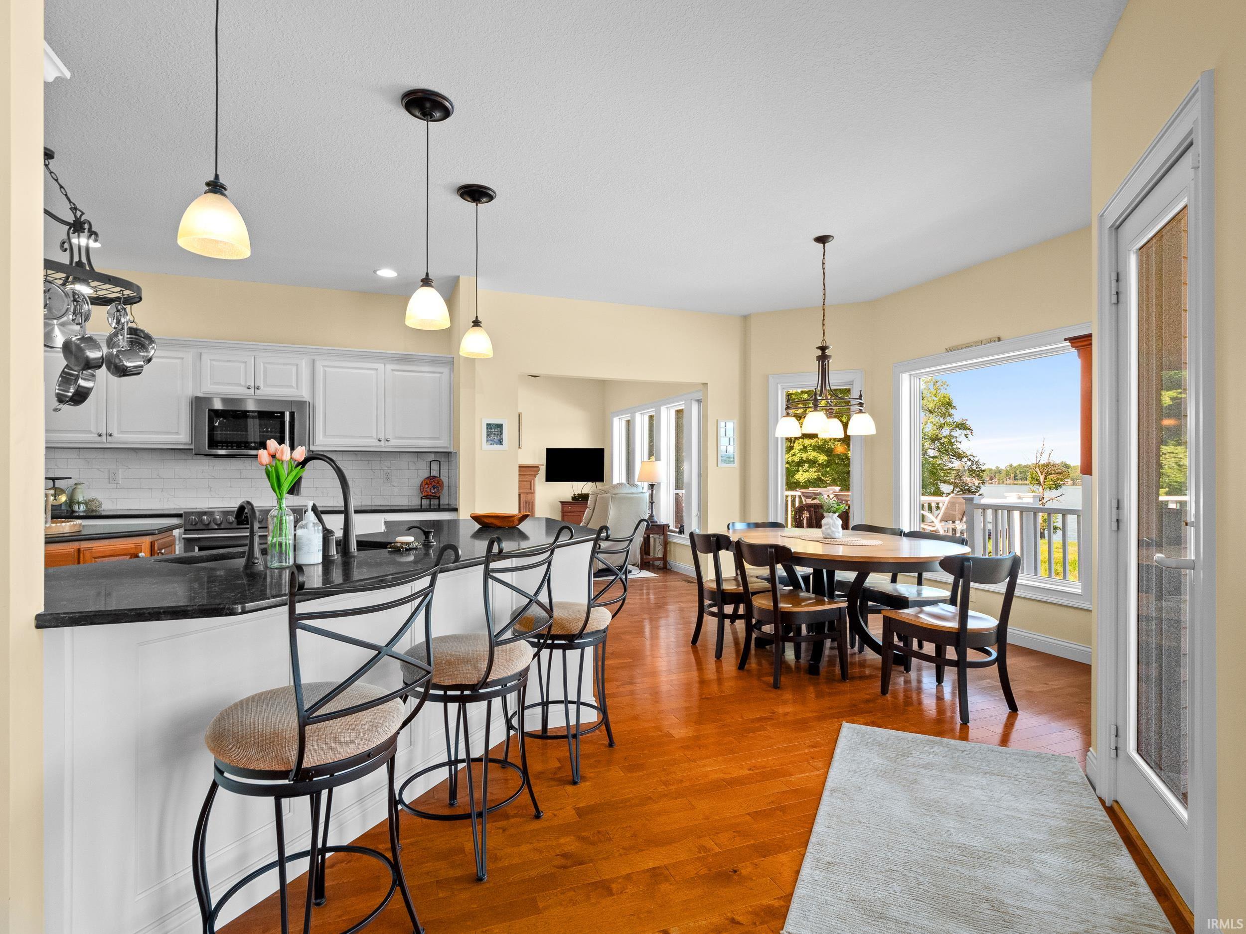 Kitchen featuring a breakfast bar area, white cabinets, tasteful backsplash, decorative light fixtures, and appliances with stainless steel finishes