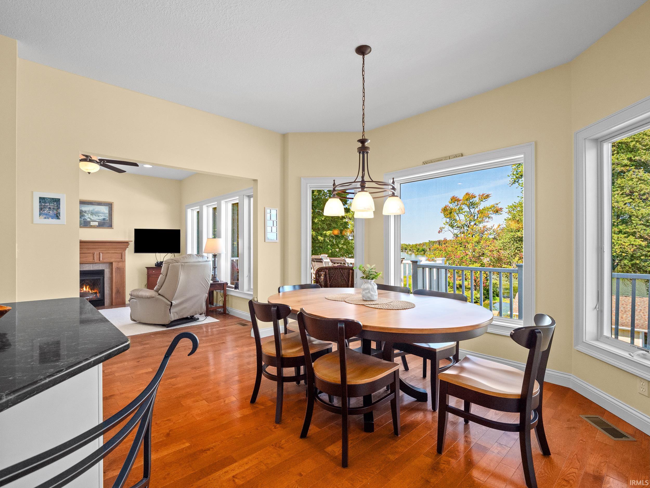 Dining room featuring a lit fireplace, light wood-style flooring, and healthy amount of natural light