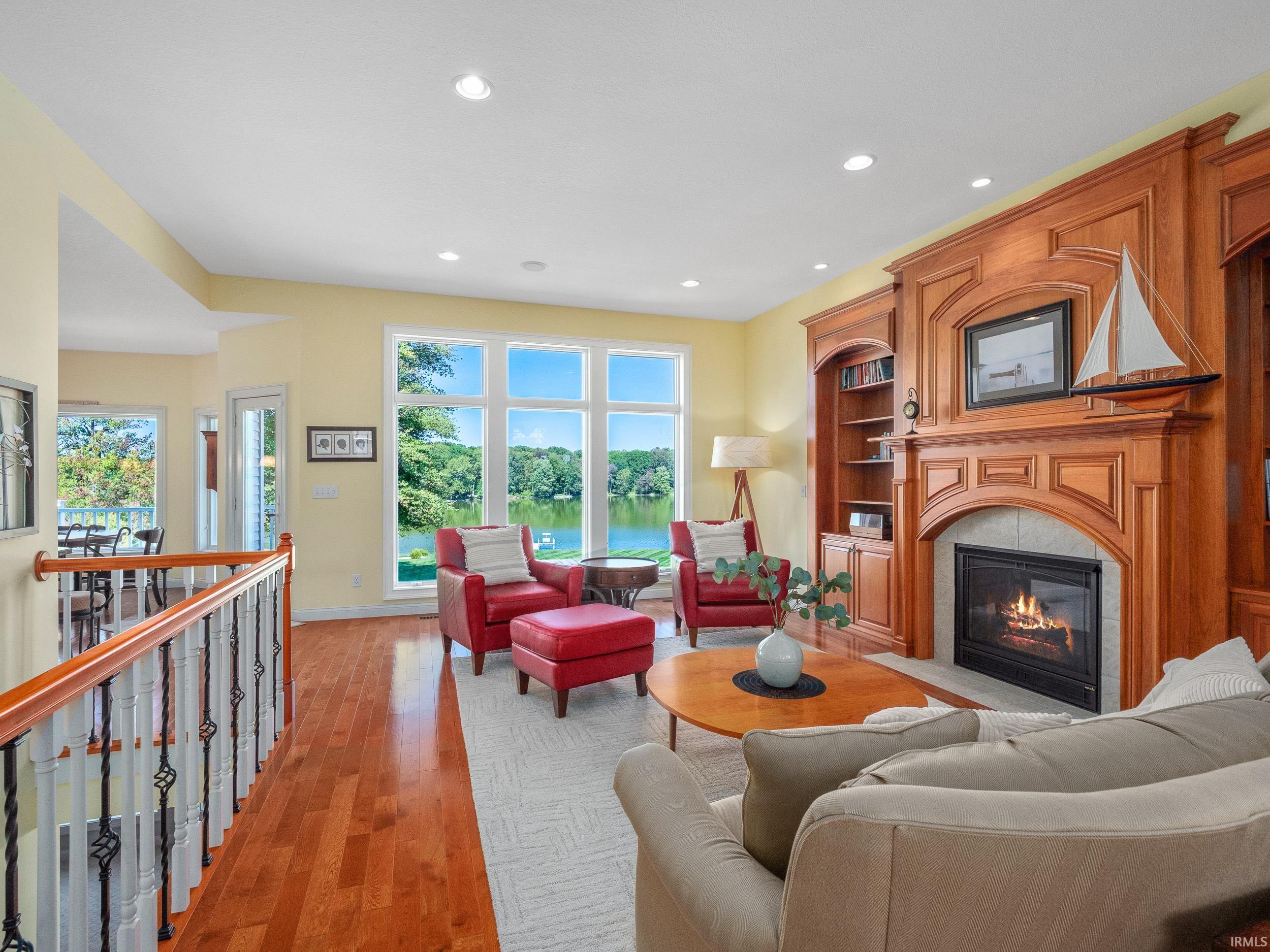 Living area featuring a fireplace with flush hearth, a water view, light wood-style flooring, recessed lighting, and built in features