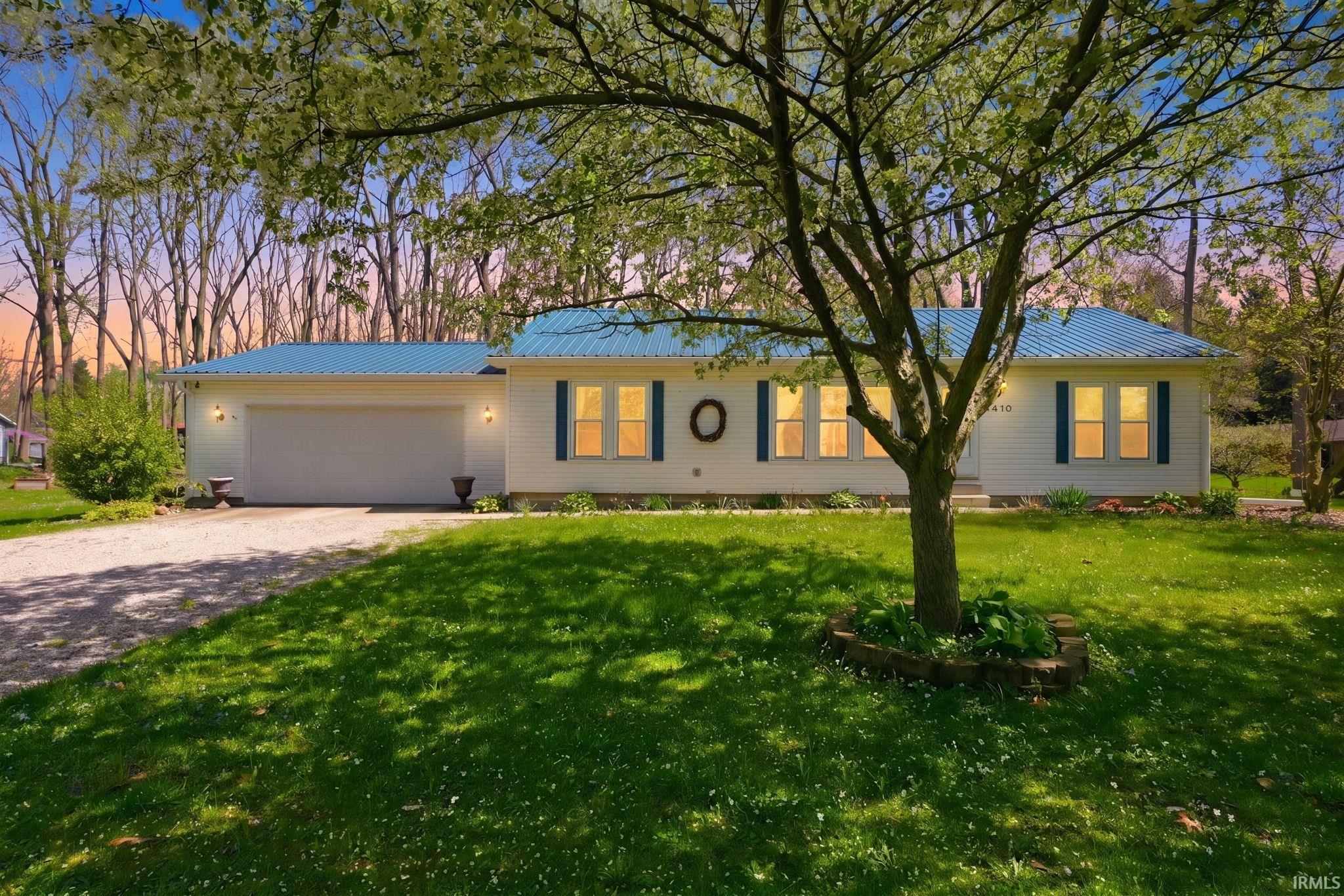 Single story home featuring a metal roof, driveway, a garage, and a front lawn