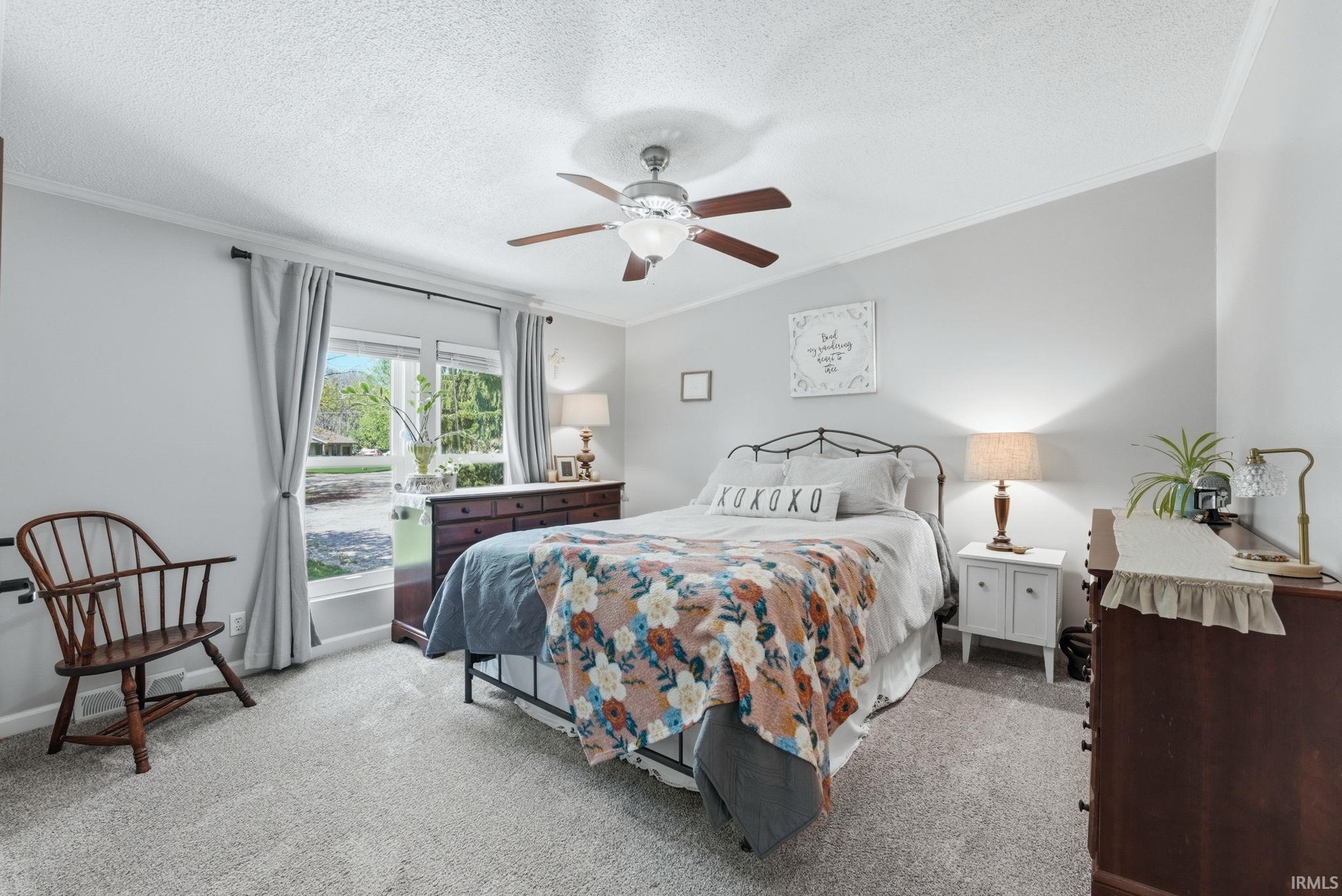 Bedroom with crown molding, light carpet, ceiling fan, and a textured ceiling