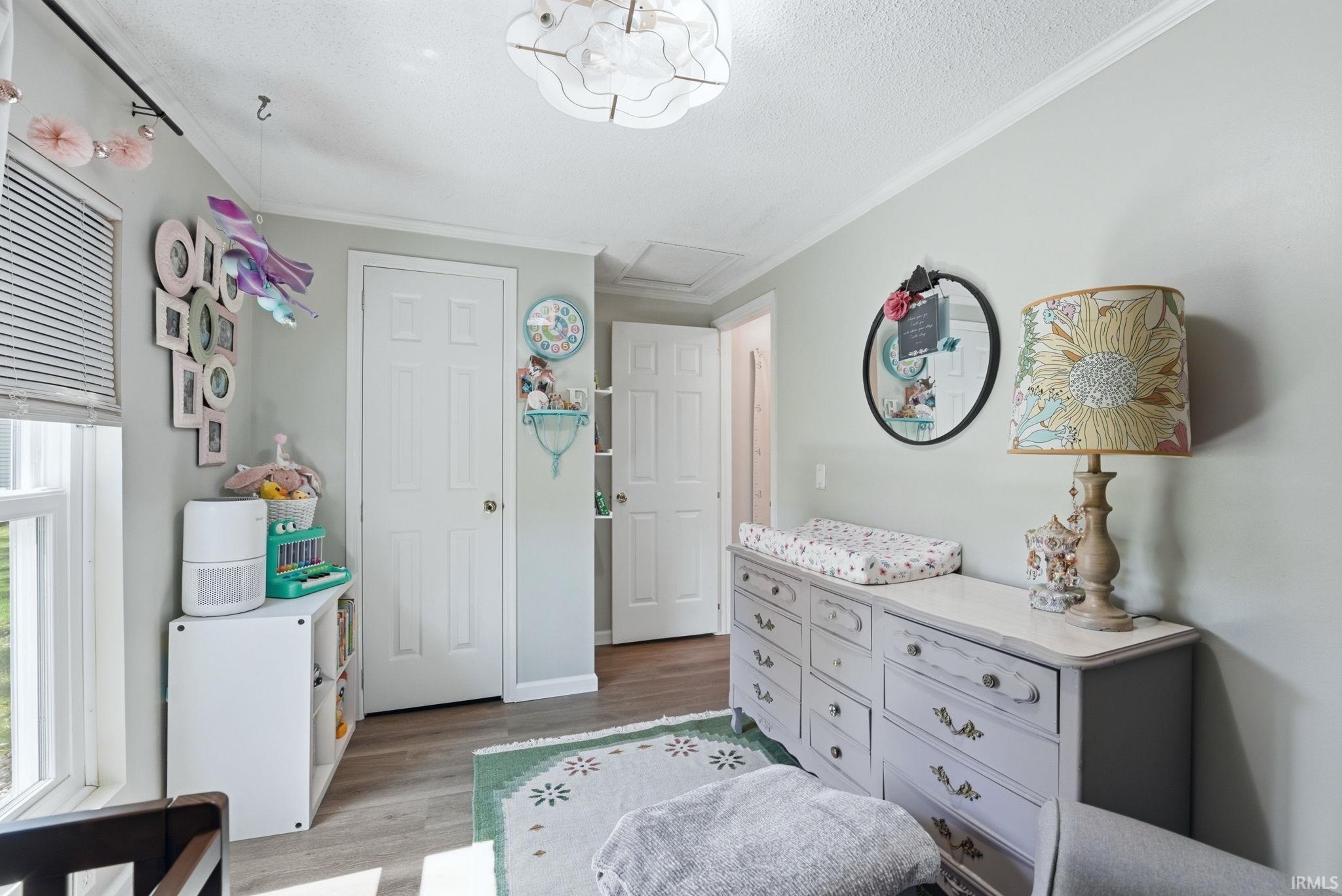 Bedroom with crown molding, light wood-style flooring, and a textured ceiling