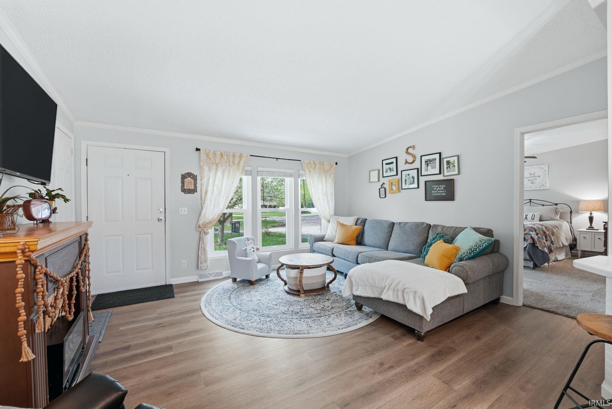 Living room featuring wood finished floors and crown molding