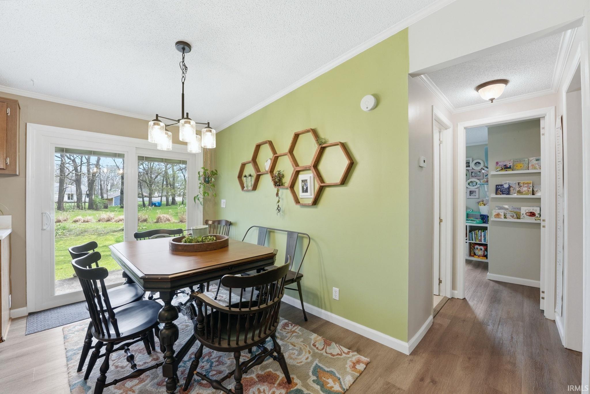 Dining area featuring ornamental molding, a textured ceiling, light wood-type flooring, and a chandelier