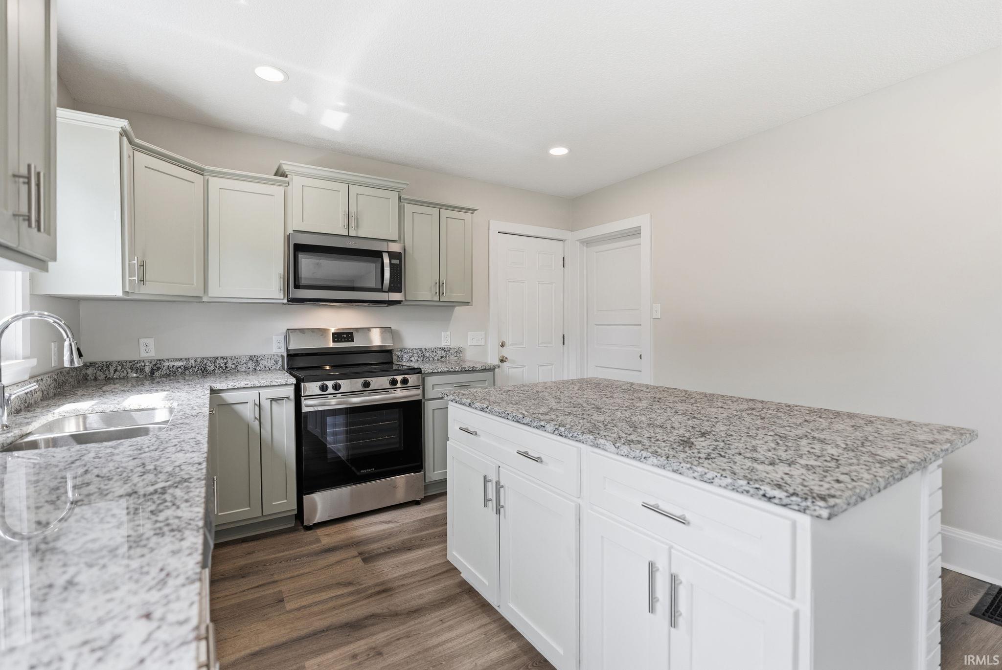 Kitchen featuring stainless steel appliances, light stone countertops, dark wood-style flooring, a kitchen island, and recessed lighting