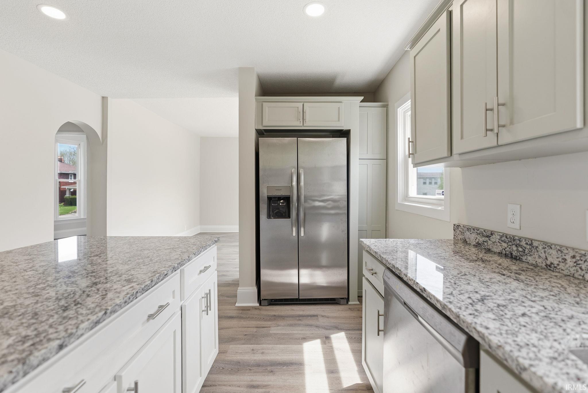 Kitchen featuring stainless steel appliances, light wood-style flooring, light stone counters, recessed lighting, and white cabinets