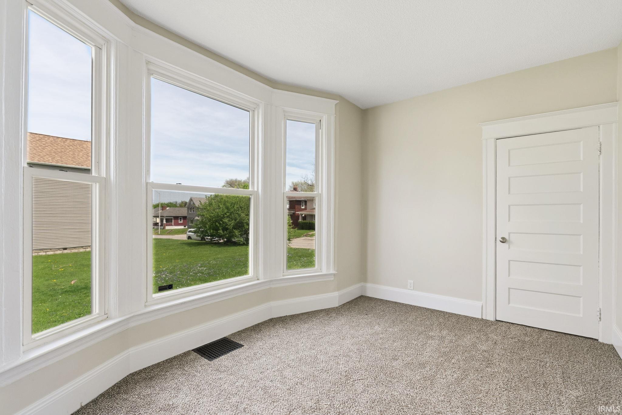 Downstairs bedroom featuring baseboards and light carpet