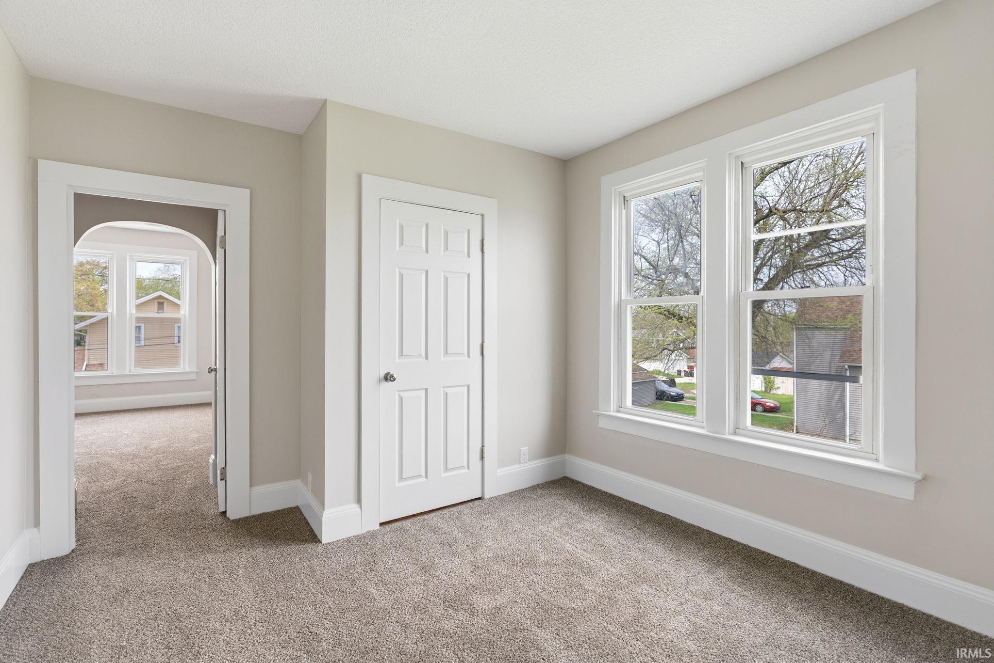 Unfurnished bedroom with light carpet and baseboards