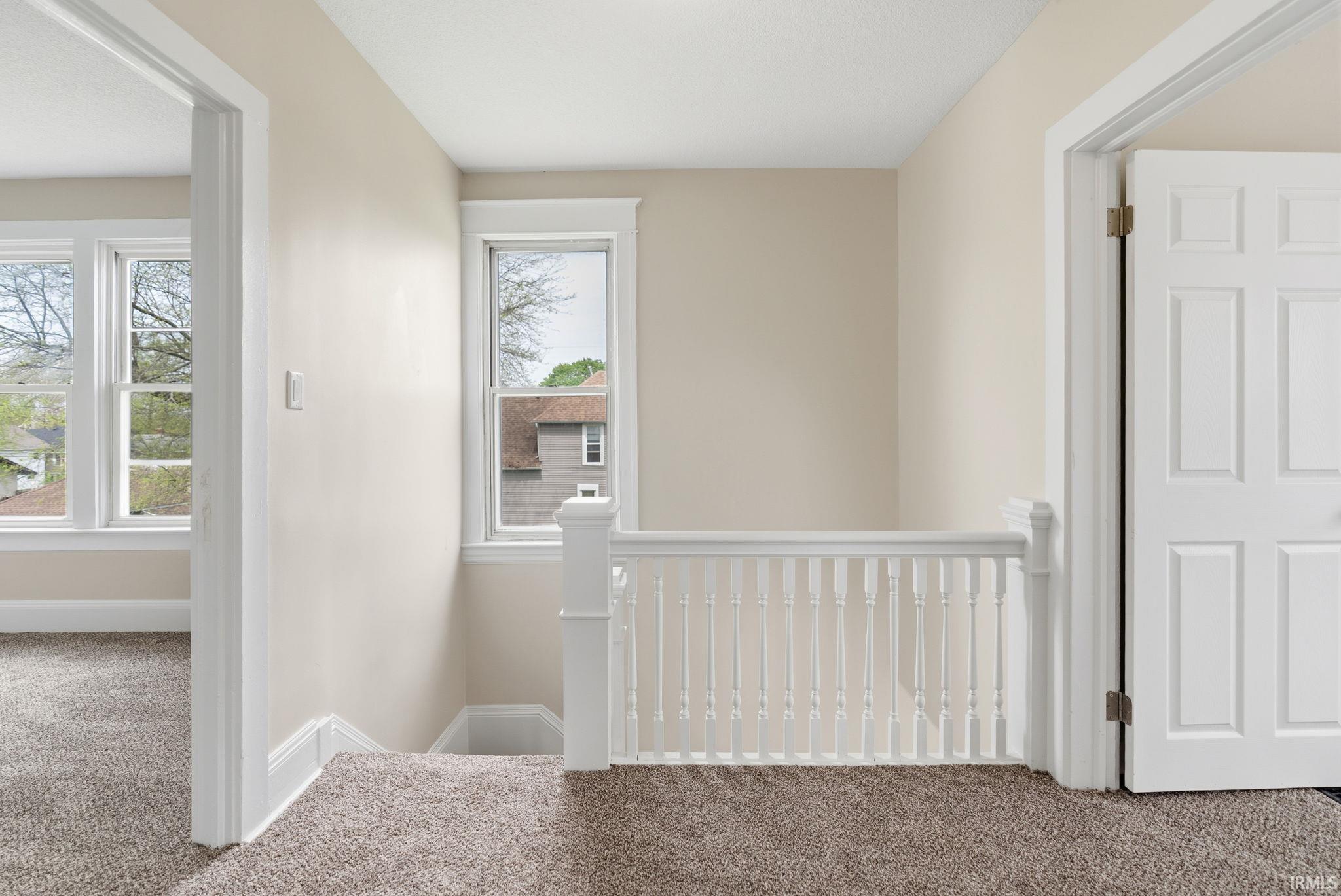 Hallway with carpet flooring and an upstairs landing