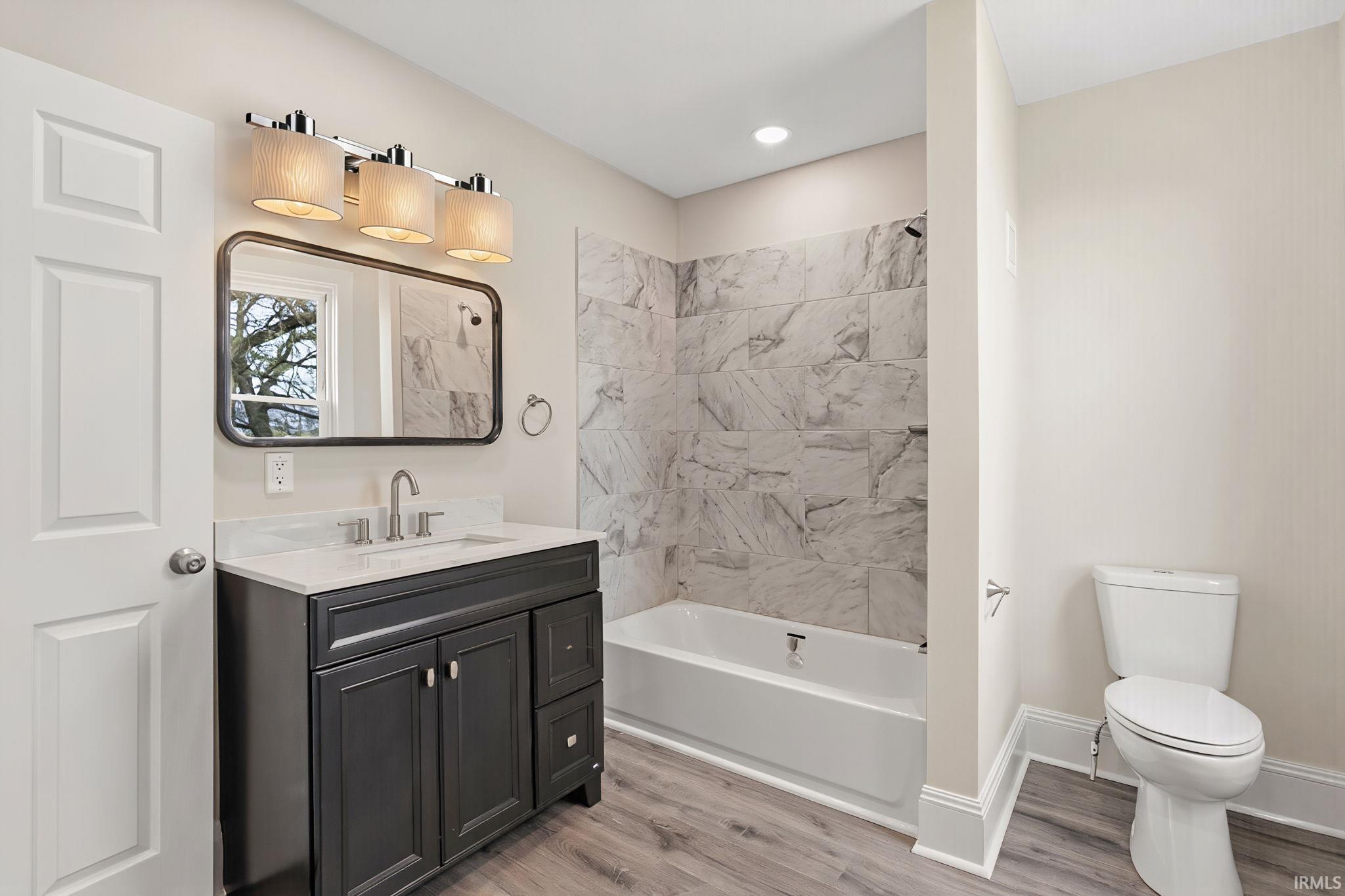 Bathroom featuring vanity, light wood-type flooring, and tub / shower combination