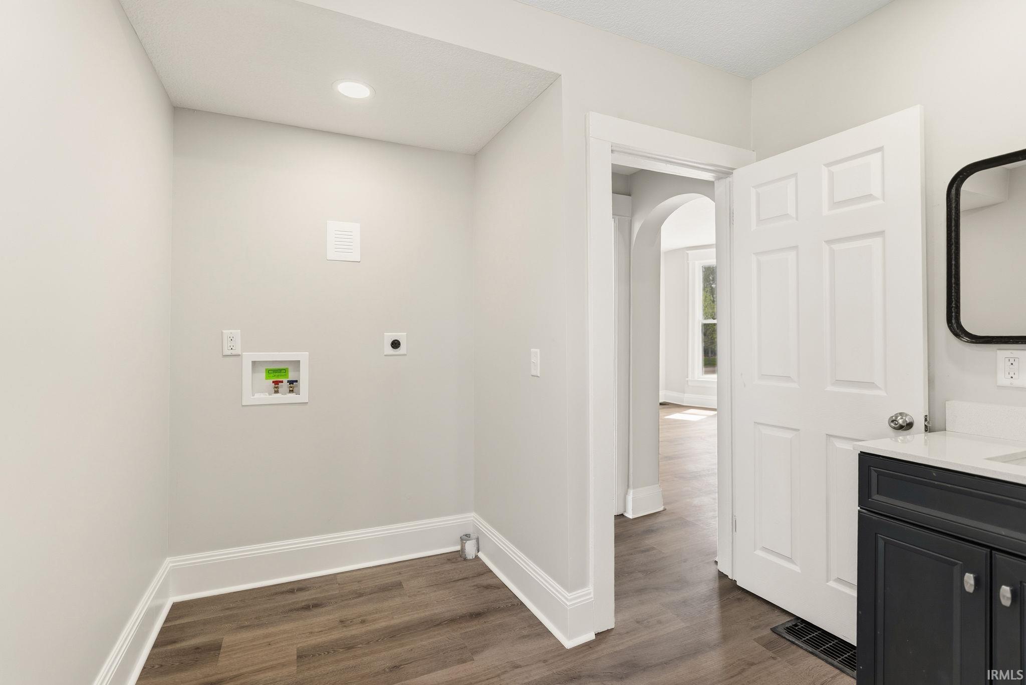 Laundry room with dark wood-style floors, arched walkways, hookup for a washing machine, hookup for an electric dryer, and recessed lighting