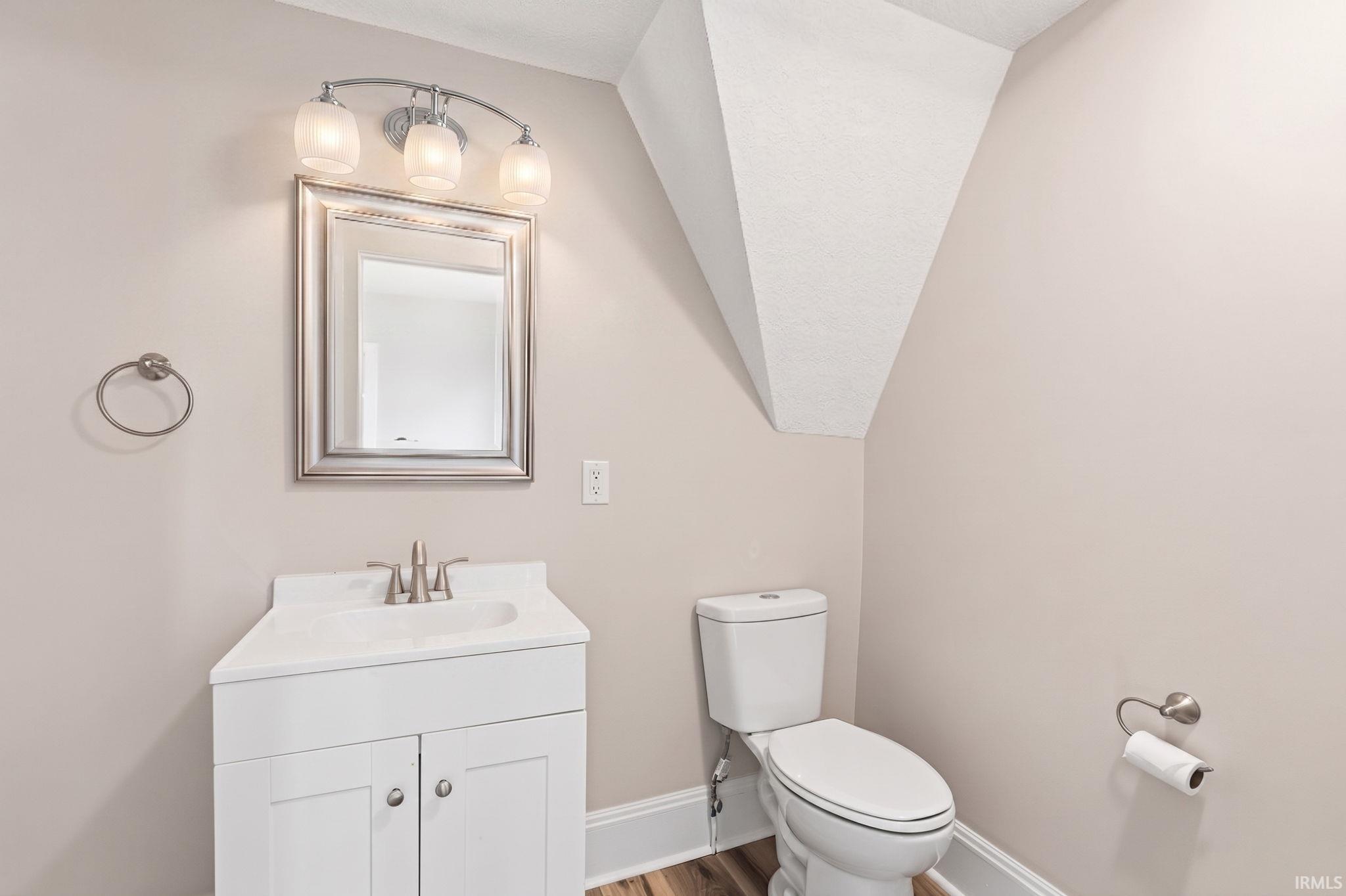 Bathroom with vanity, wood finished floors, and lofted ceiling