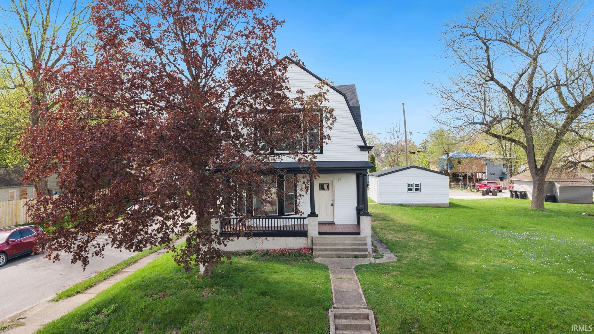 View of front of property with covered porch and a front yard