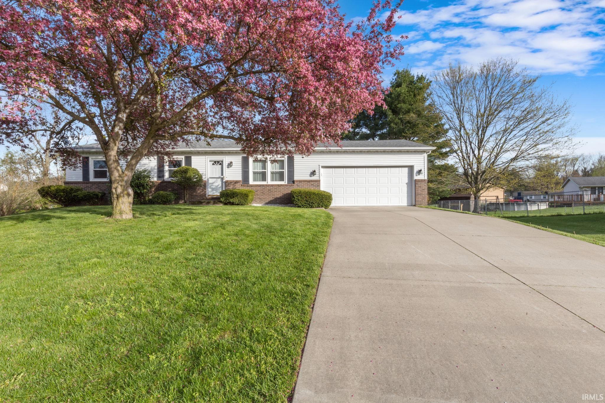 View of front of home with brick siding, a garage, a front lawn, and concrete driveway