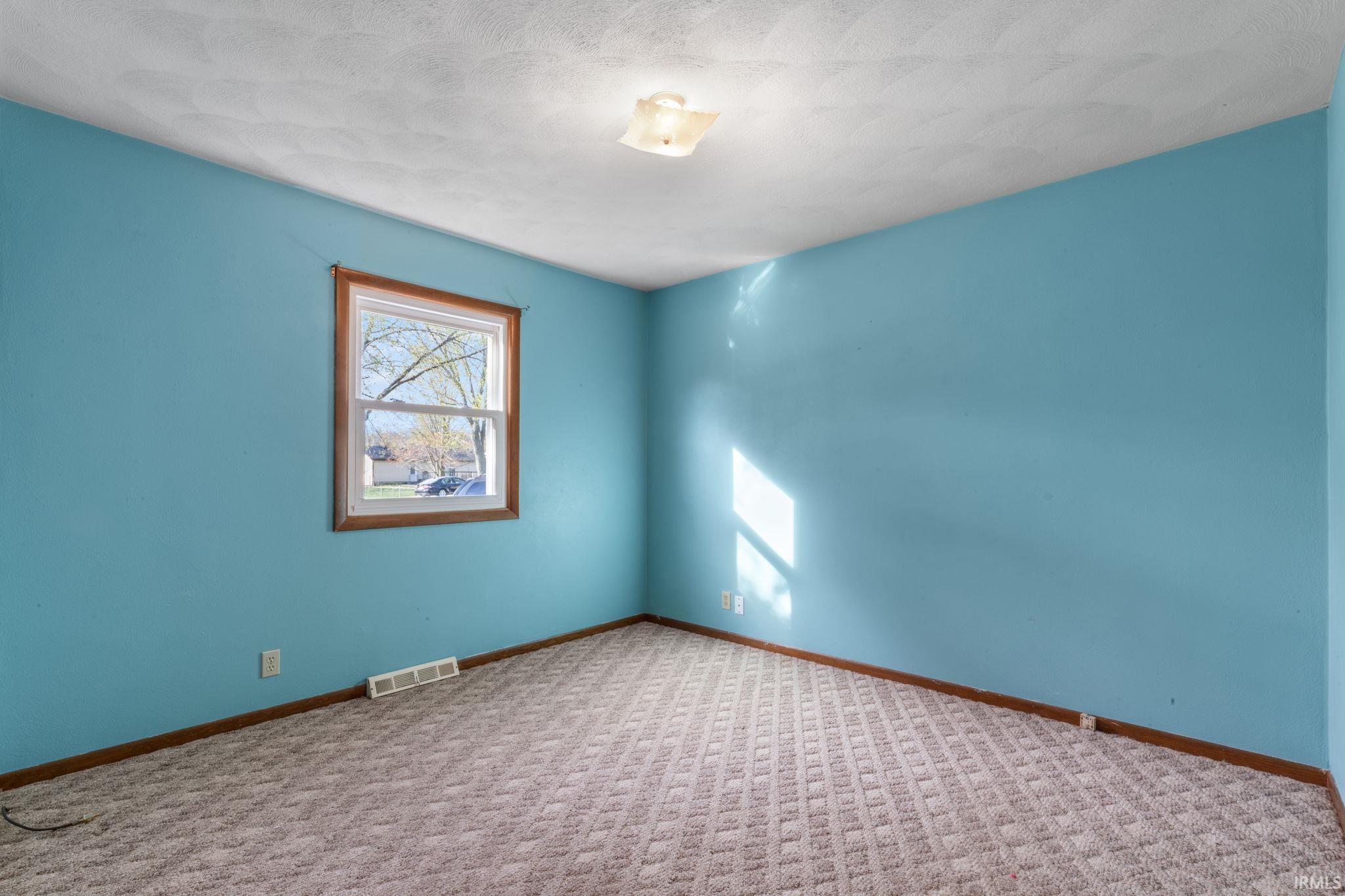 Unfurnished room with carpet and a textured ceiling