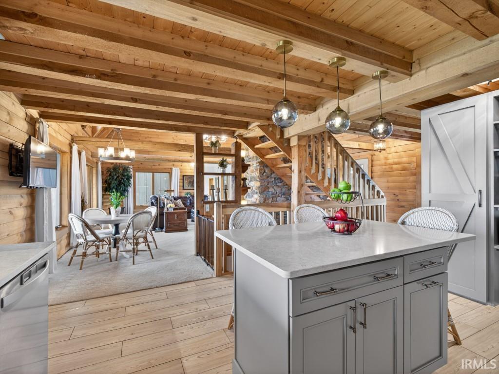 Kitchen featuring a kitchen breakfast bar, dishwasher, a kitchen island, light stone countertops, and light wood-type flooring