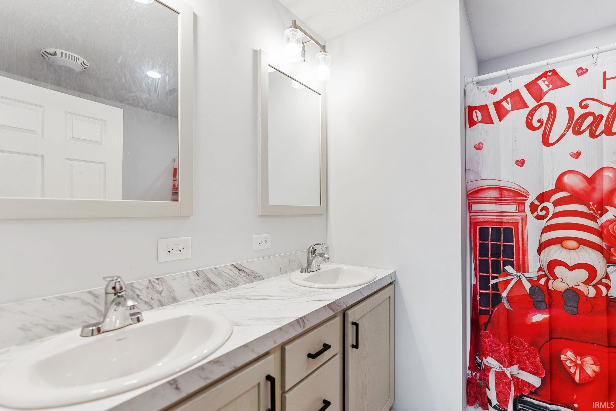 Bathroom with double vanity and a shower with shower curtain