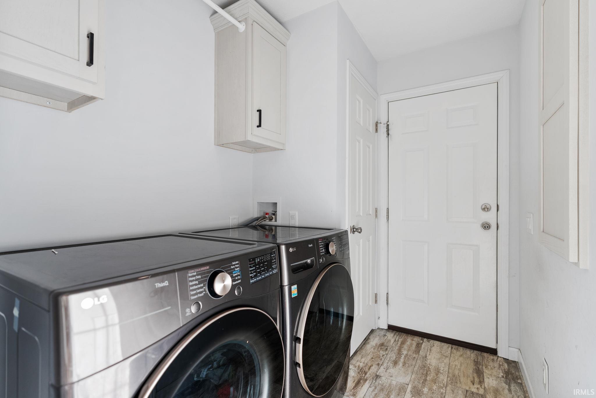 Laundry area with light wood finished floors, cabinet space, and independent washer and dryer