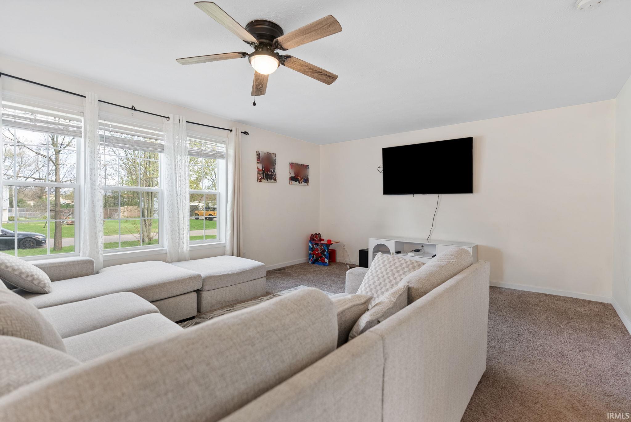 Living room featuring carpet flooring and a ceiling fan