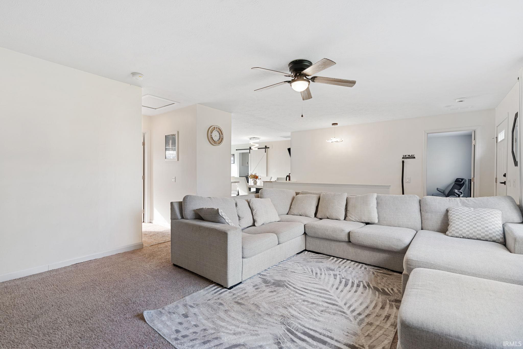 Carpeted living area featuring a ceiling fan and baseboards