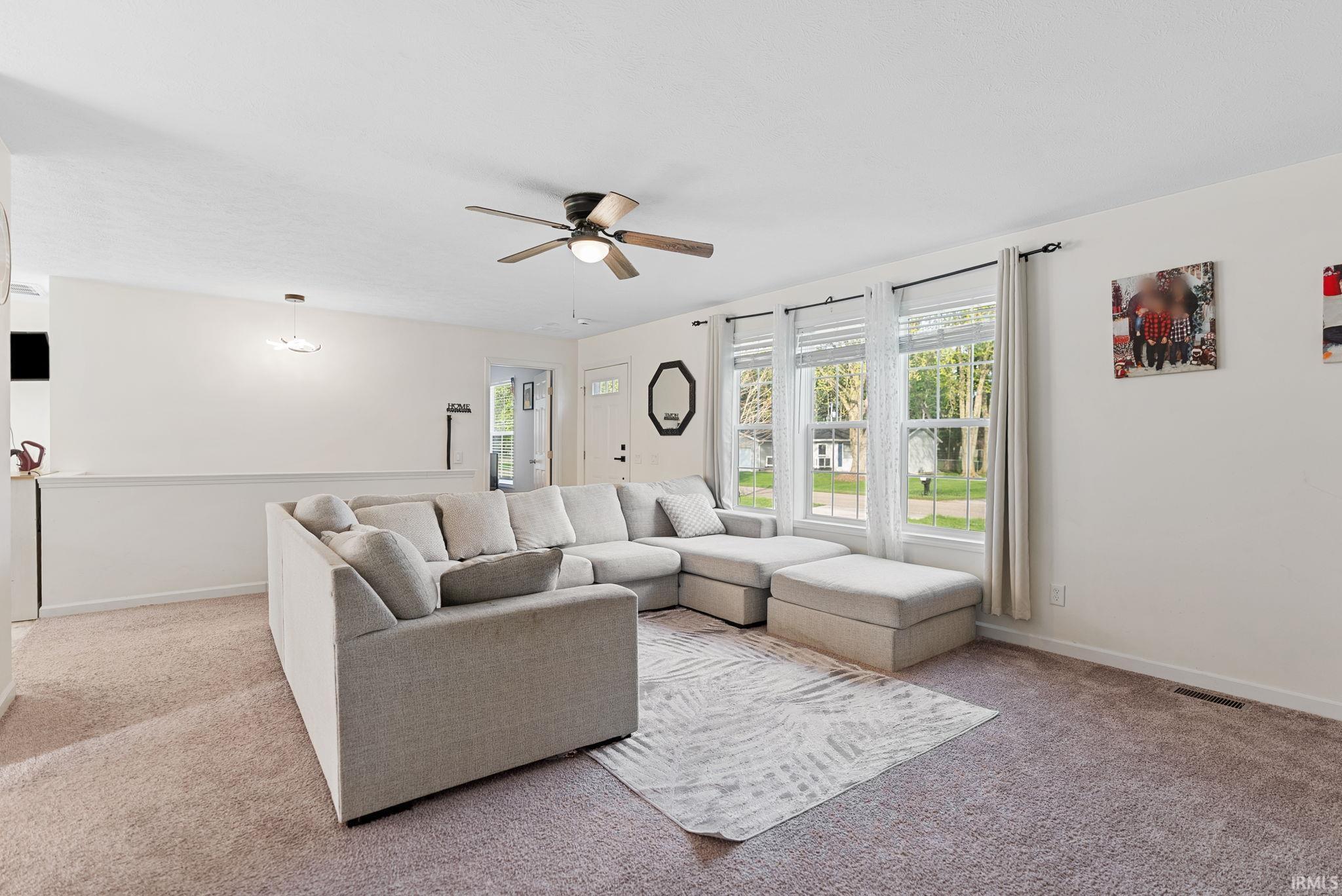 Living area featuring carpet, plenty of natural light, and ceiling fan