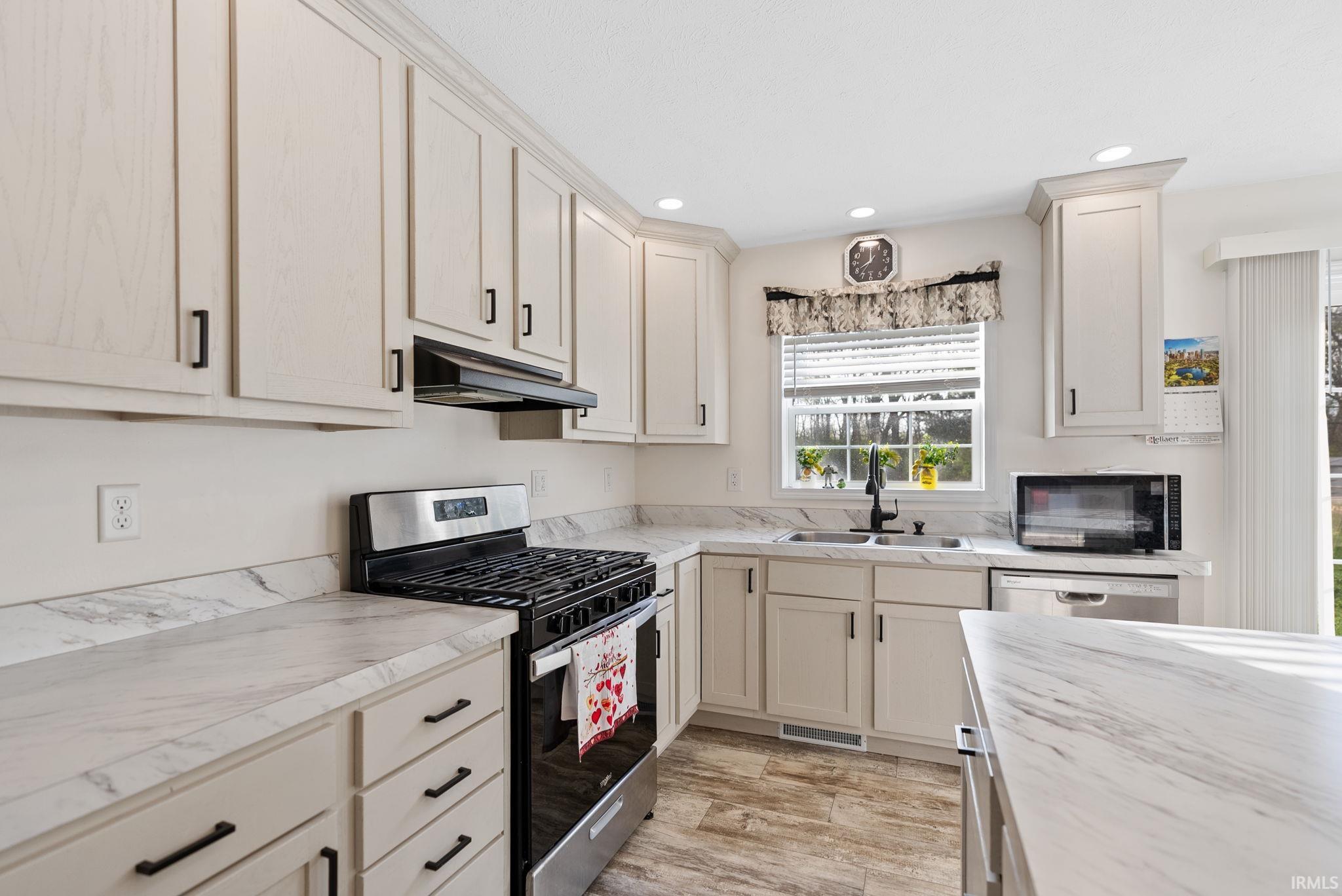 Kitchen with stainless steel appliances, light countertops, light wood-type flooring, and recessed lighting