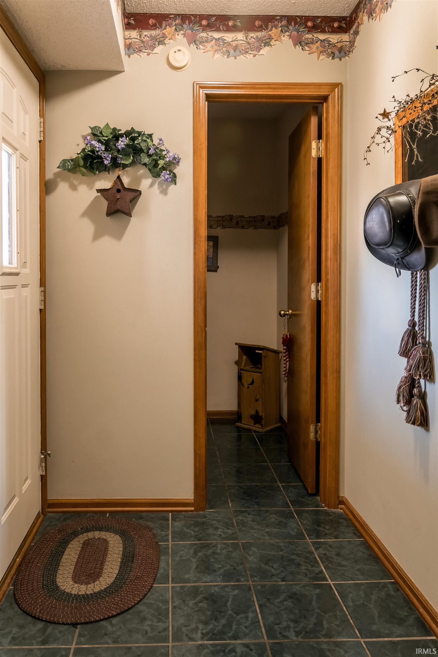 Corridor with a textured ceiling and dark tile patterned flooring