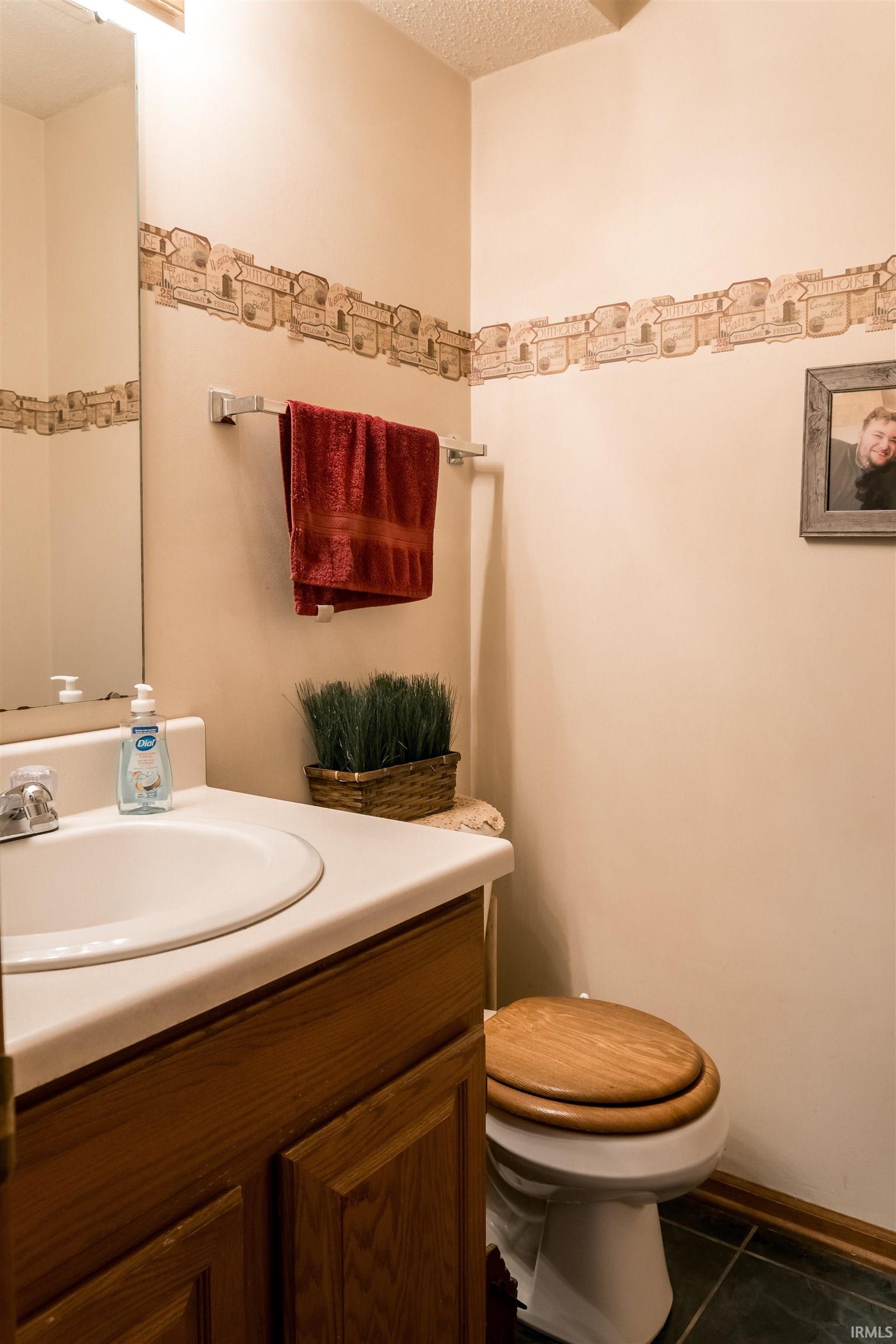 Bathroom featuring vanity, dark tile patterned floors, and a textured ceiling
