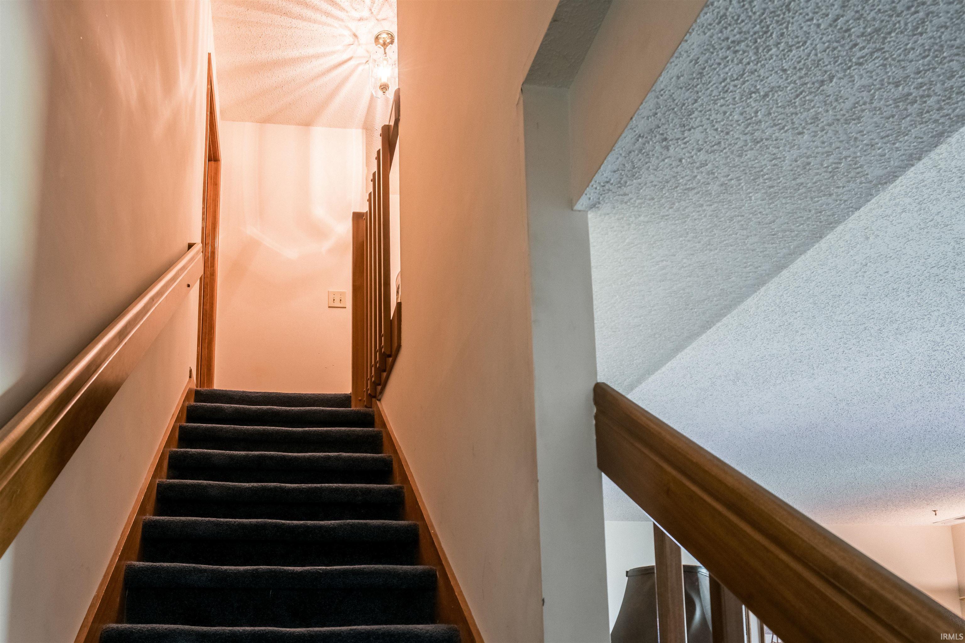 Staircase featuring a textured ceiling