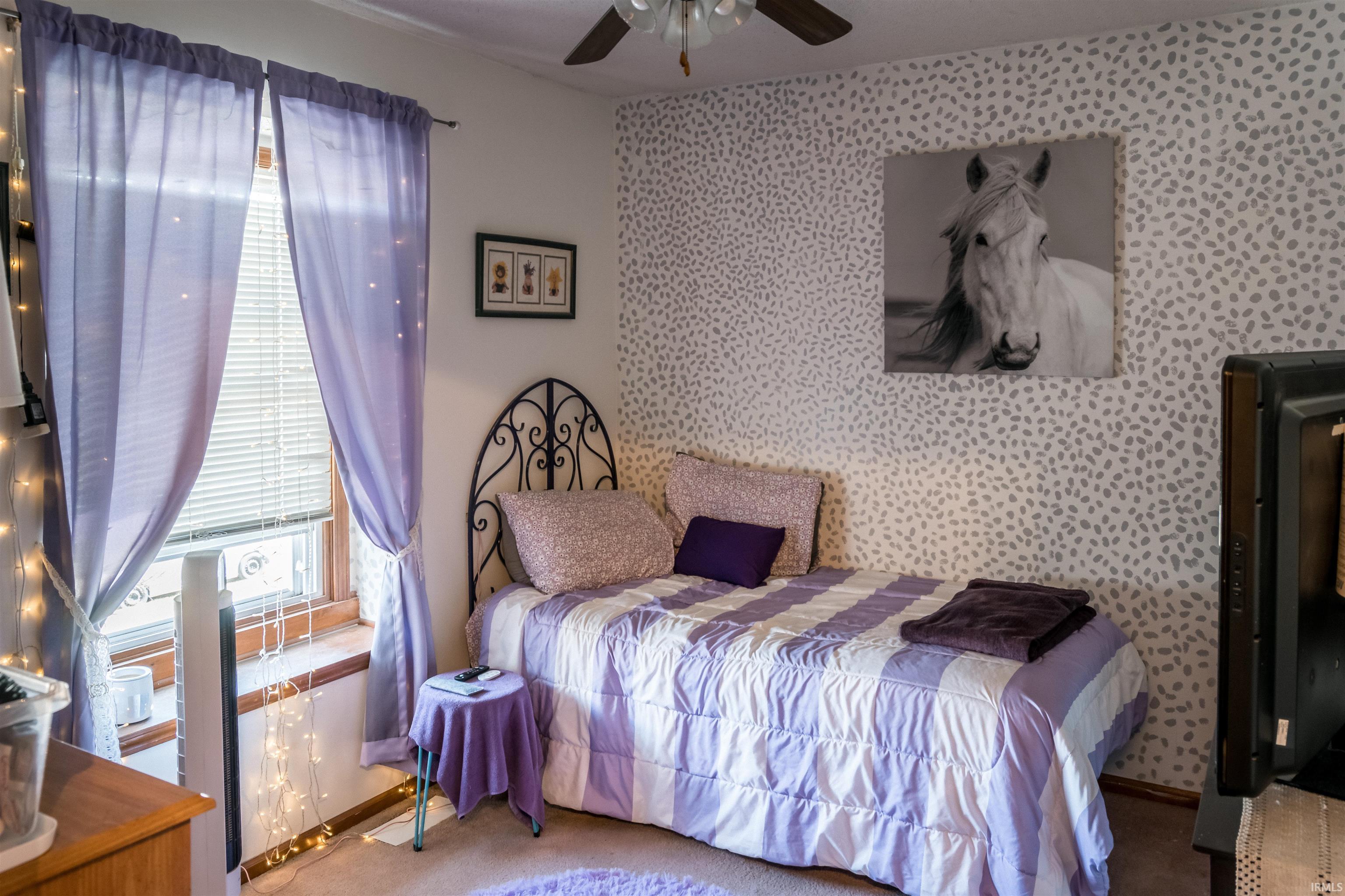 Bedroom featuring wallpapered walls, an accent wall, carpet, and a ceiling fan