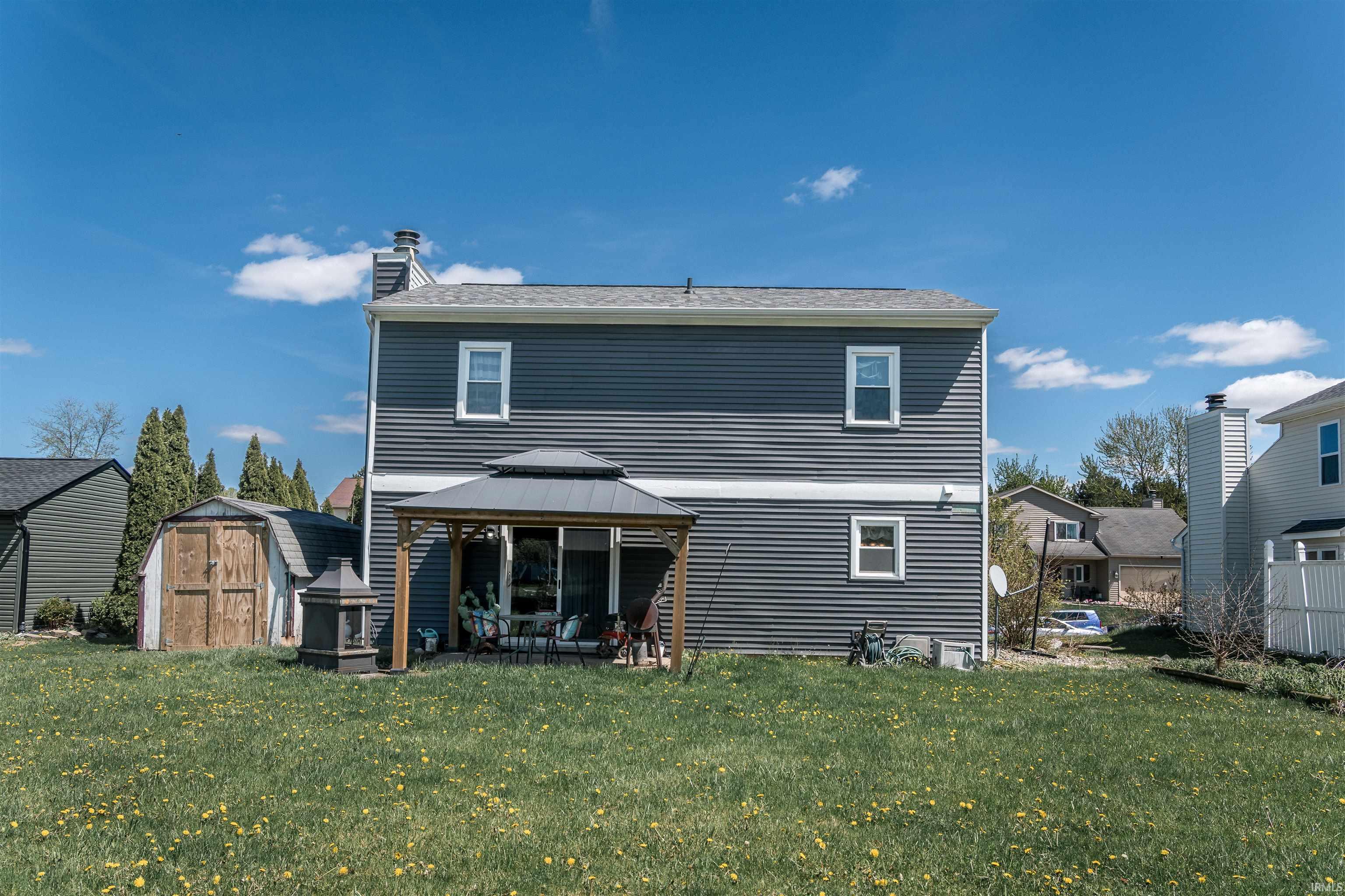 Back of property featuring a storage unit, a yard, a chimney, and a gazebo