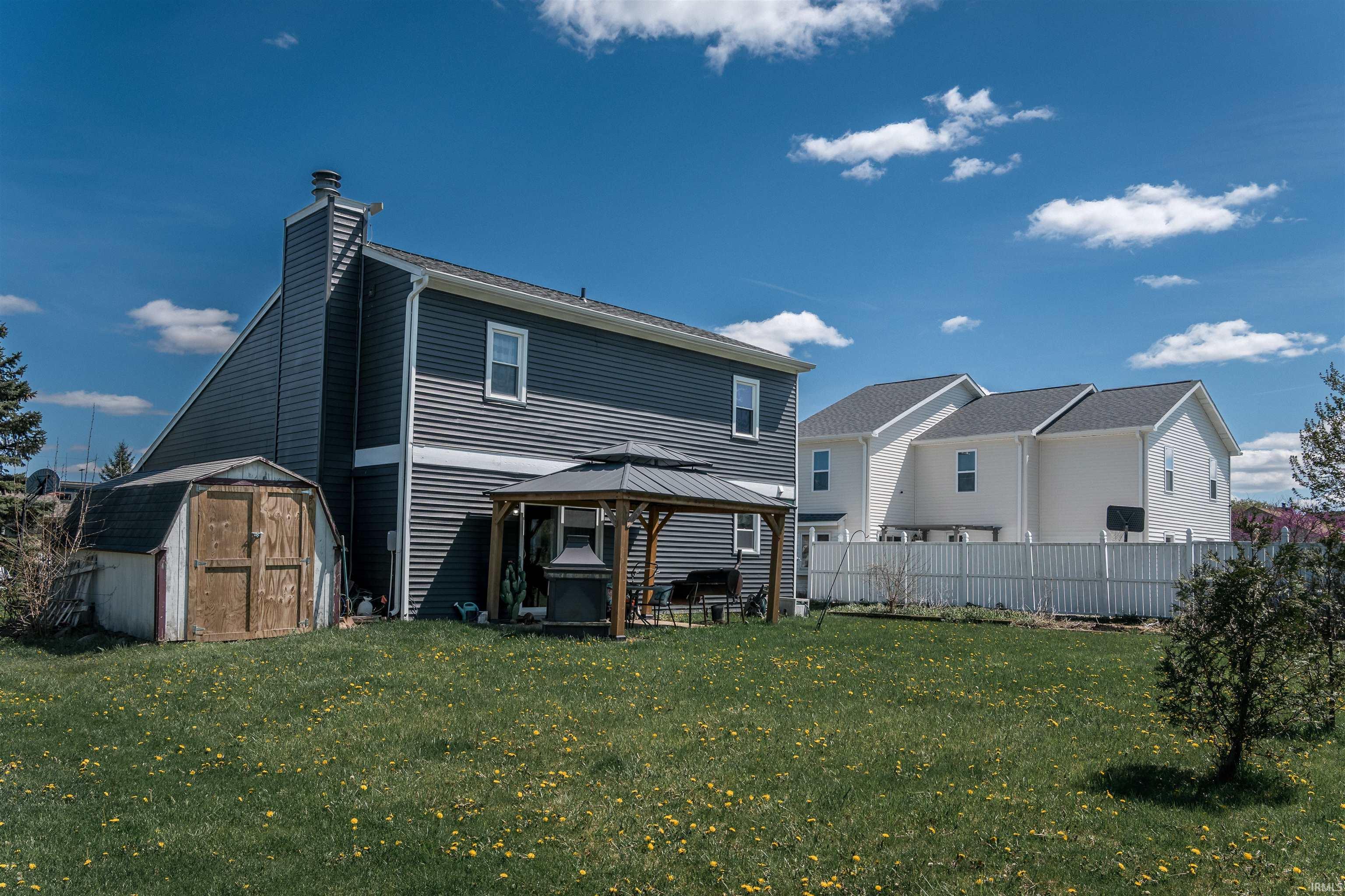 Rear view of house featuring a shed, a gazebo, a chimney, and a patio