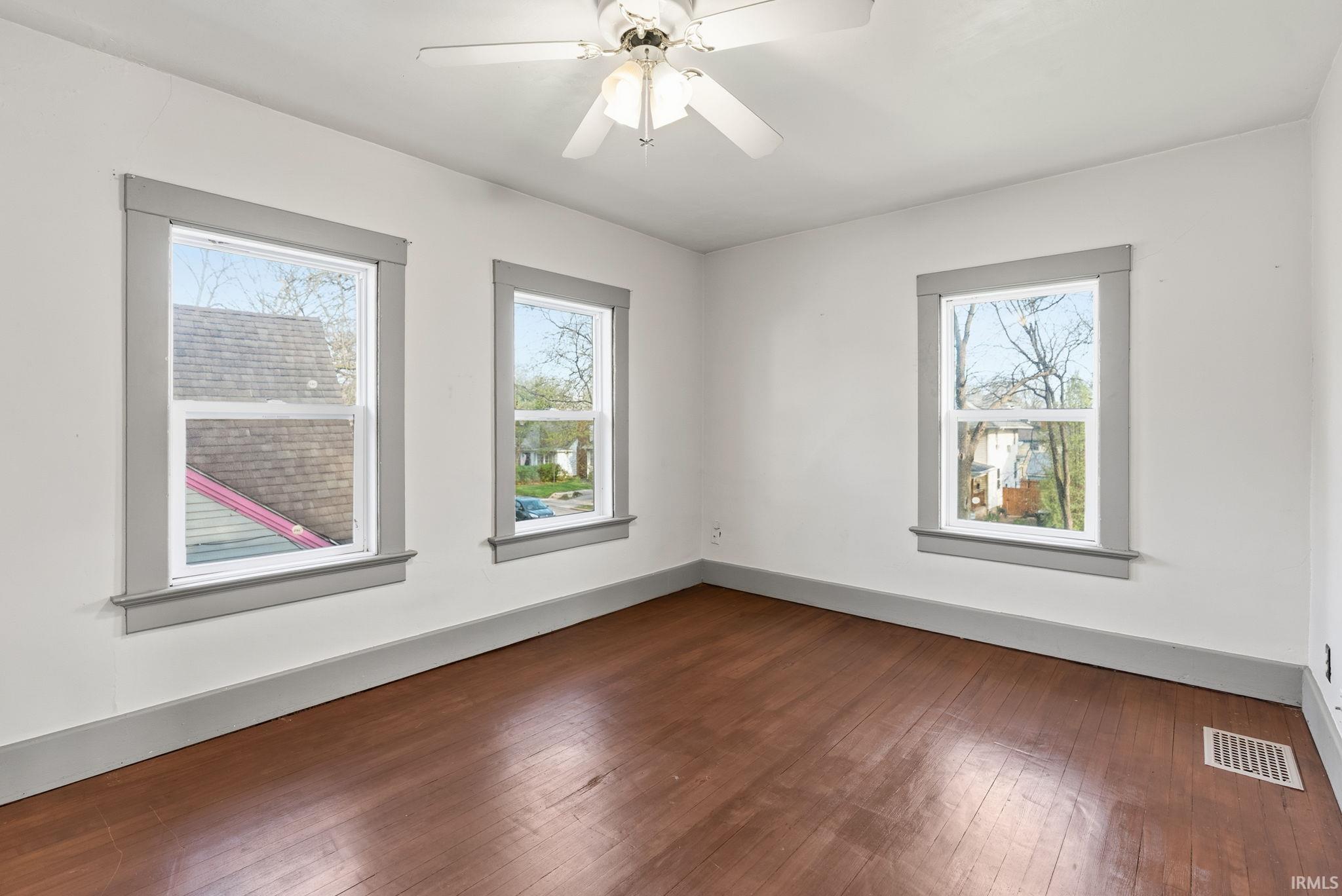 Spare room featuring dark wood-type flooring and ceiling fan