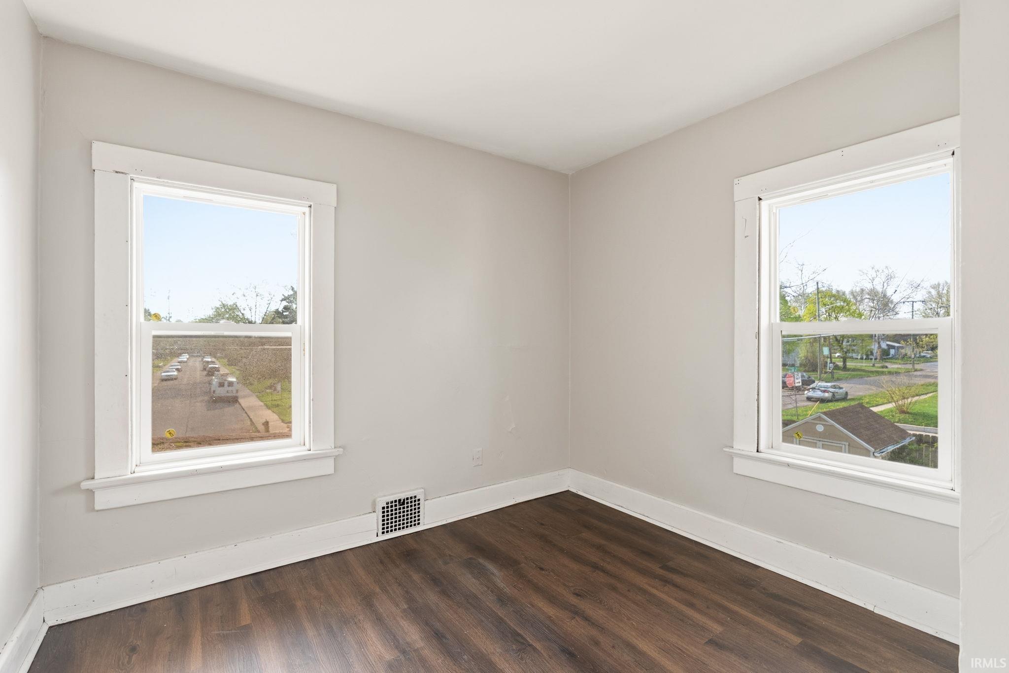 Spare room featuring baseboards and dark wood finished floors