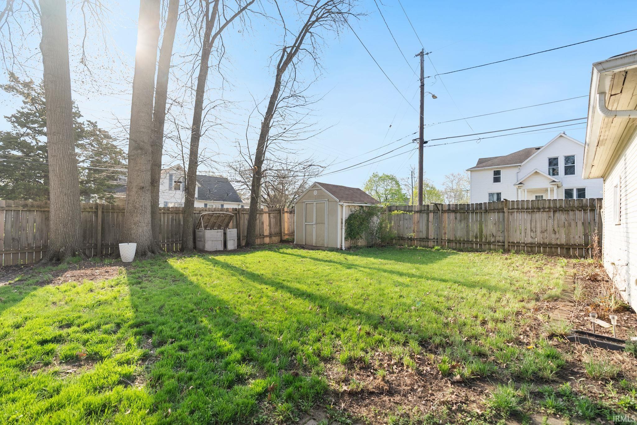 Fenced backyard featuring a shed