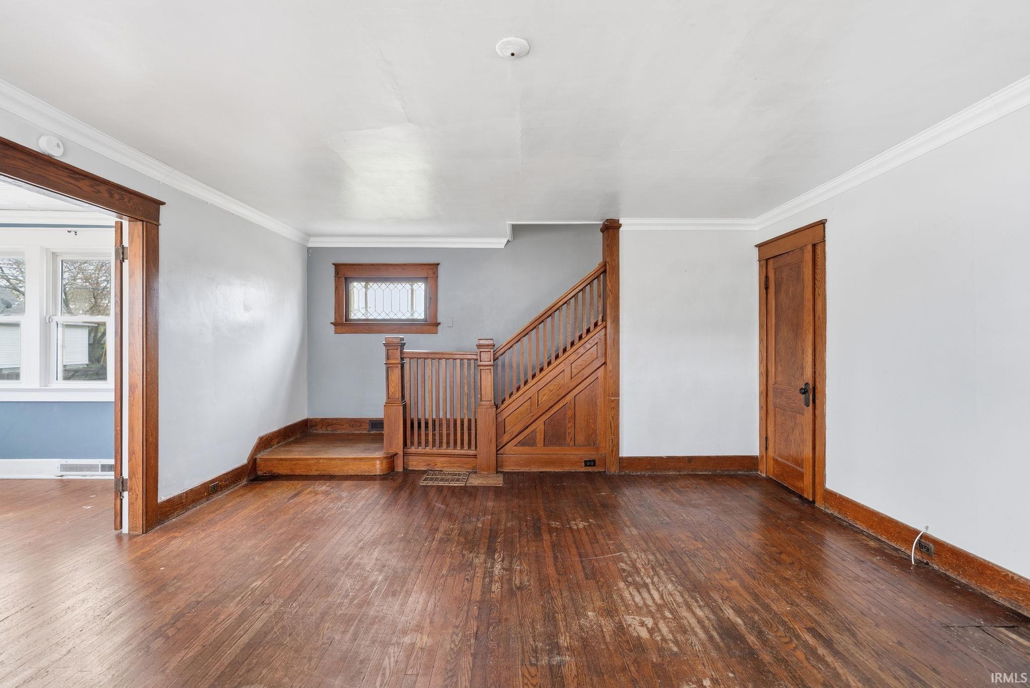 Spare room featuring dark wood-type flooring and ornamental molding