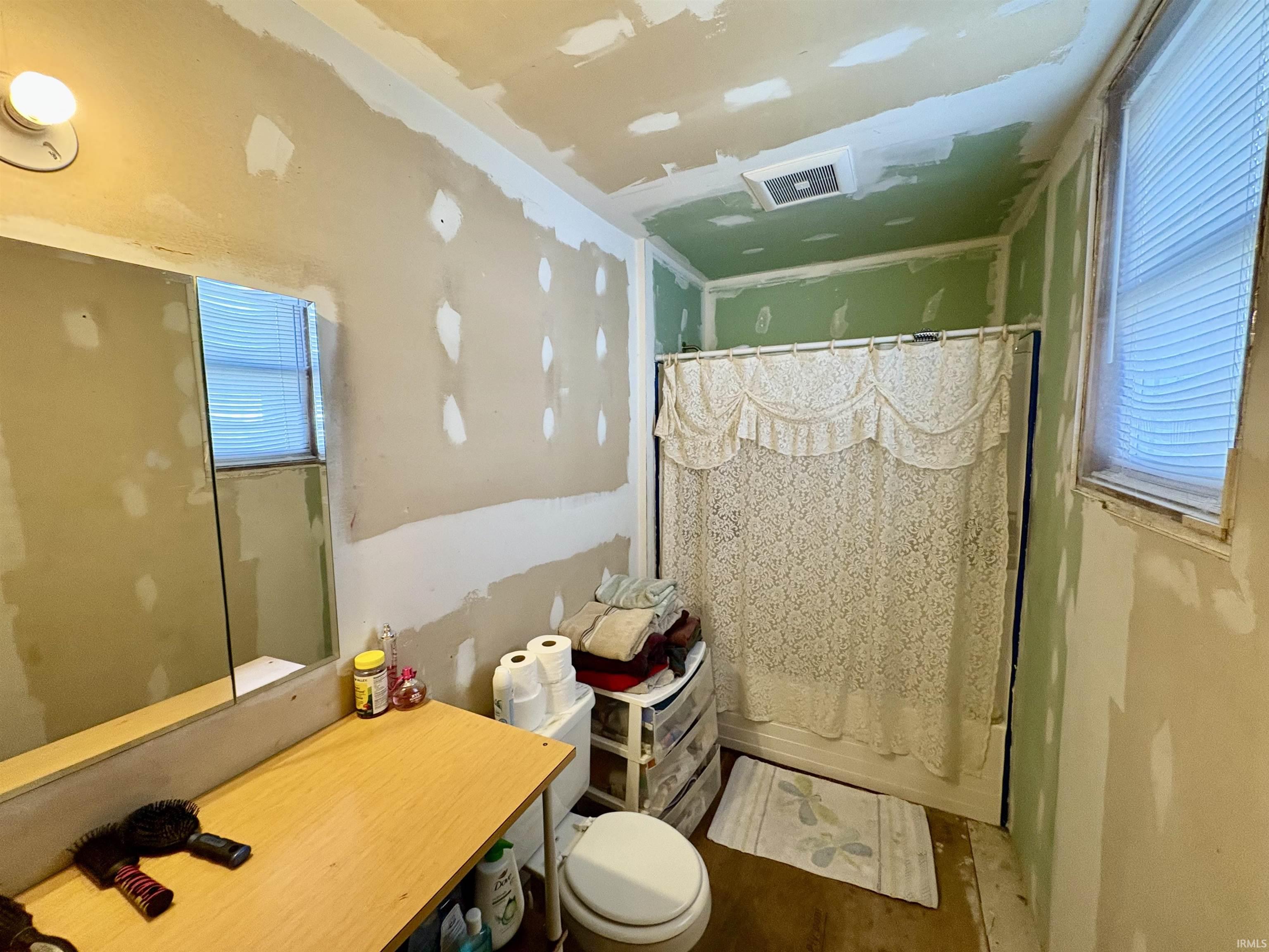Bathroom with shower / bathtub combination with curtain, vanity, and healthy amount of natural light