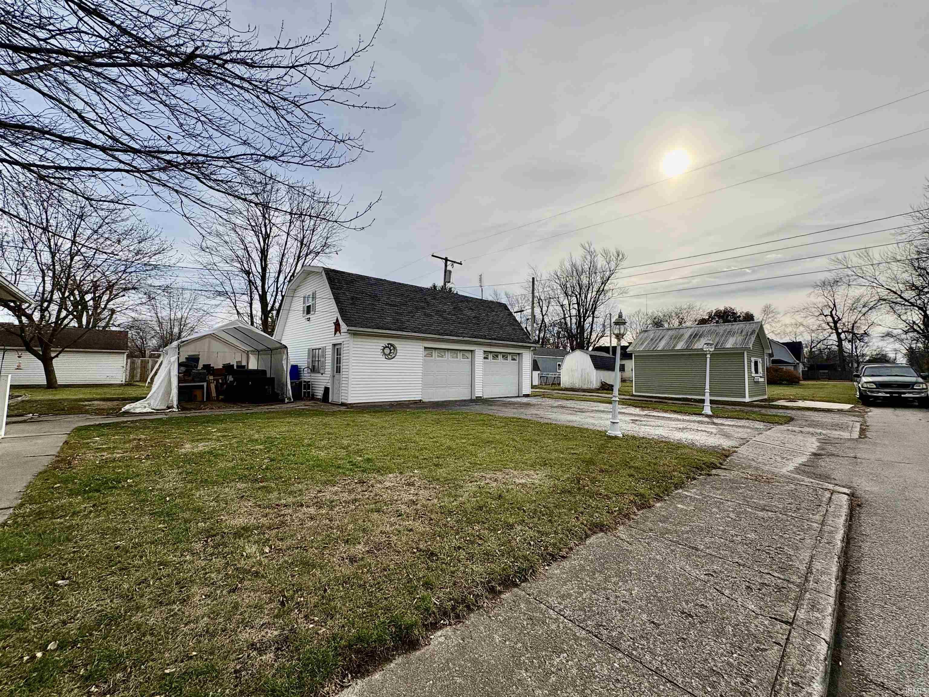 View of side of property featuring an outdoor structure, a lawn, a garage, and driveway
