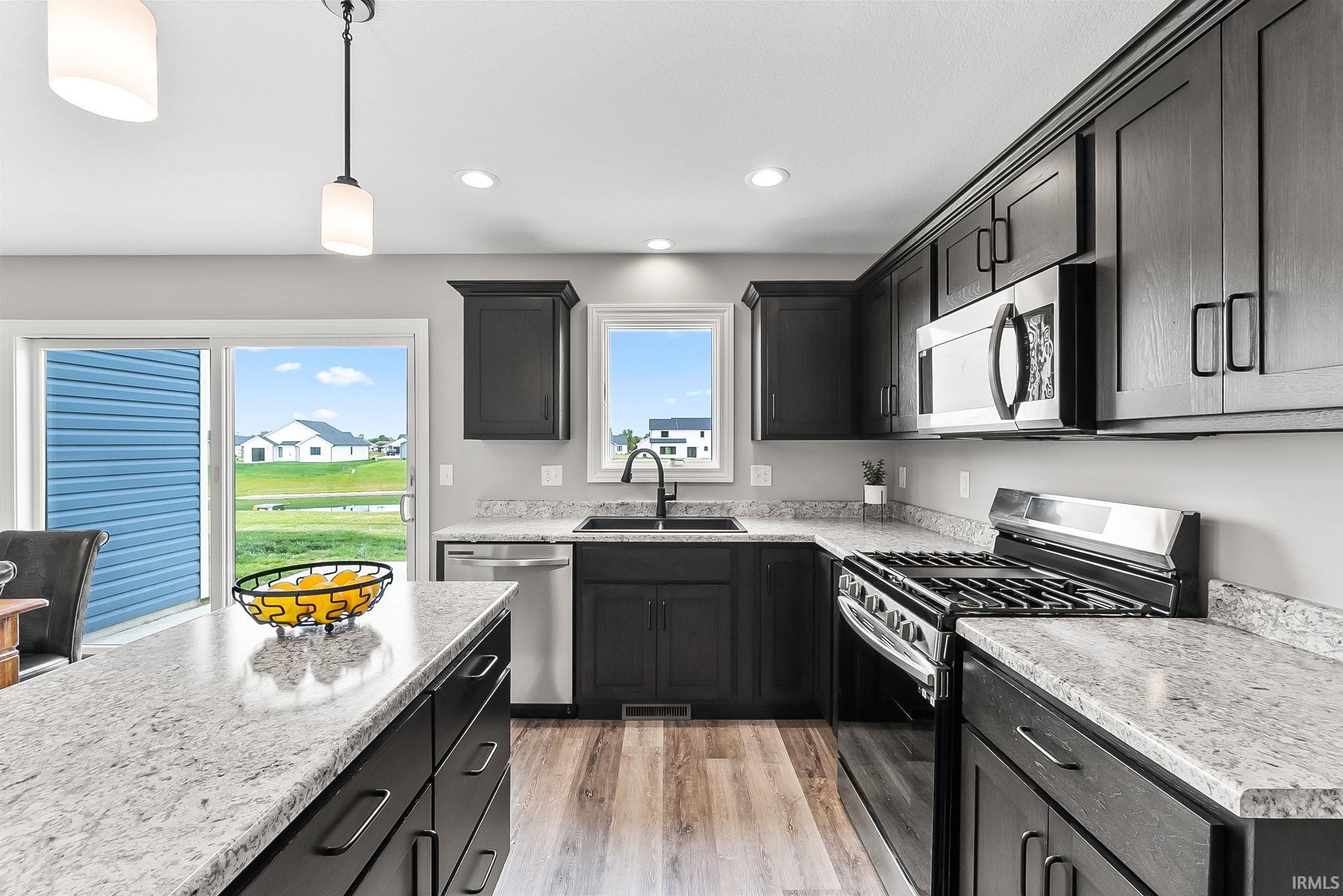 Spacious kitchen featuring dark wood cabinetry, light-toned countertops, and wood-finish flooring