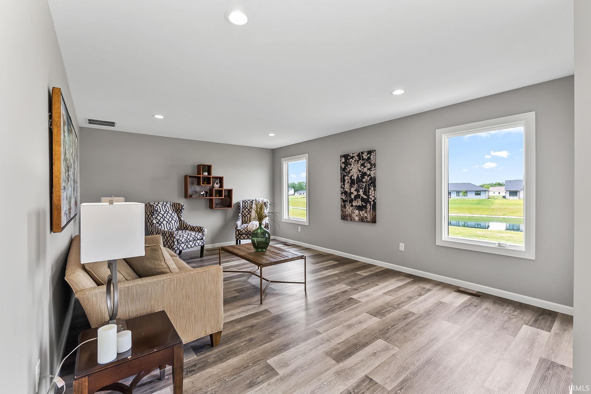 Spacious room featuring wood-finish flooring, recessed lighting, and ample natural light from multiple windows