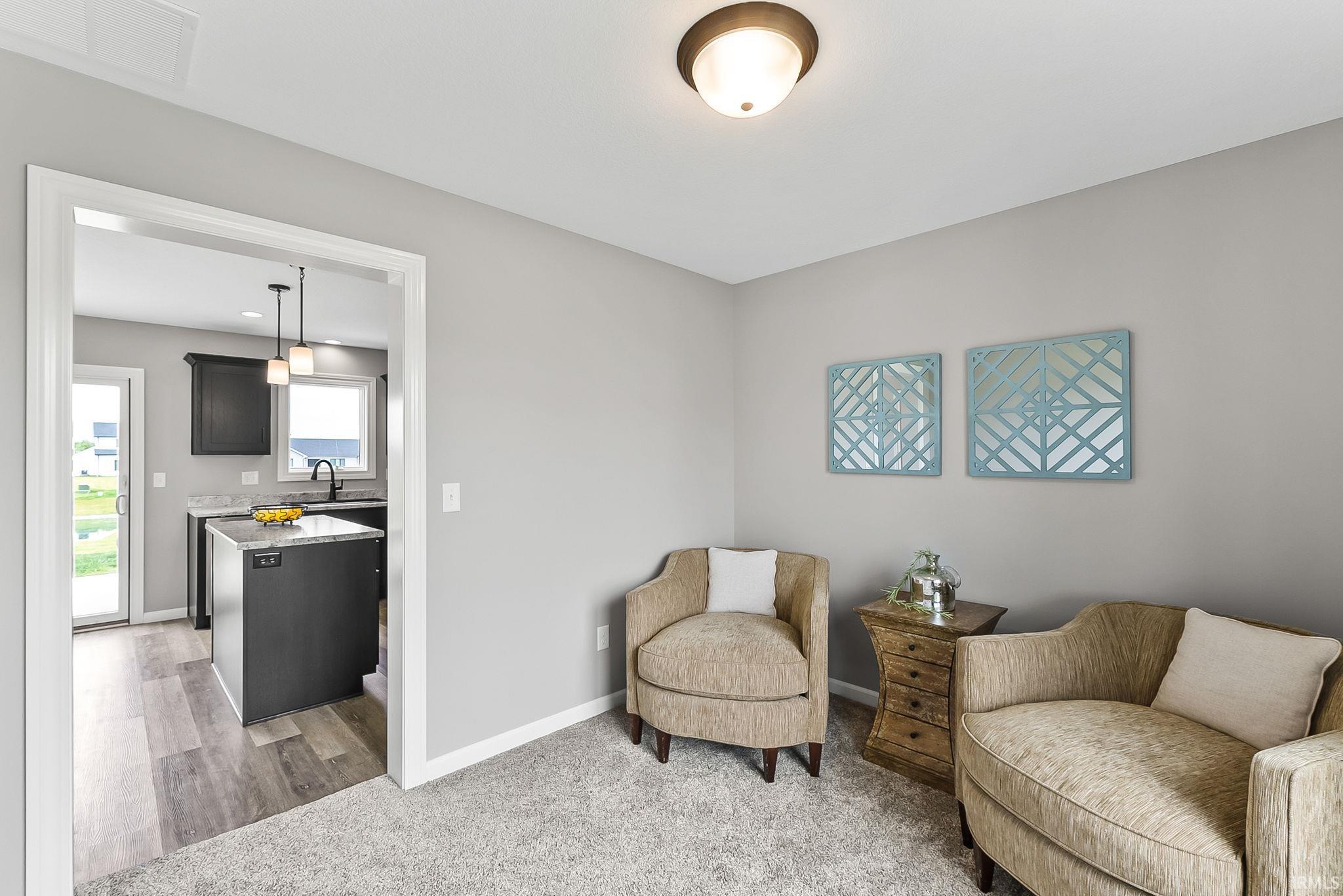 Open doorway leading to a kitchen with dark cabinetry and a central island