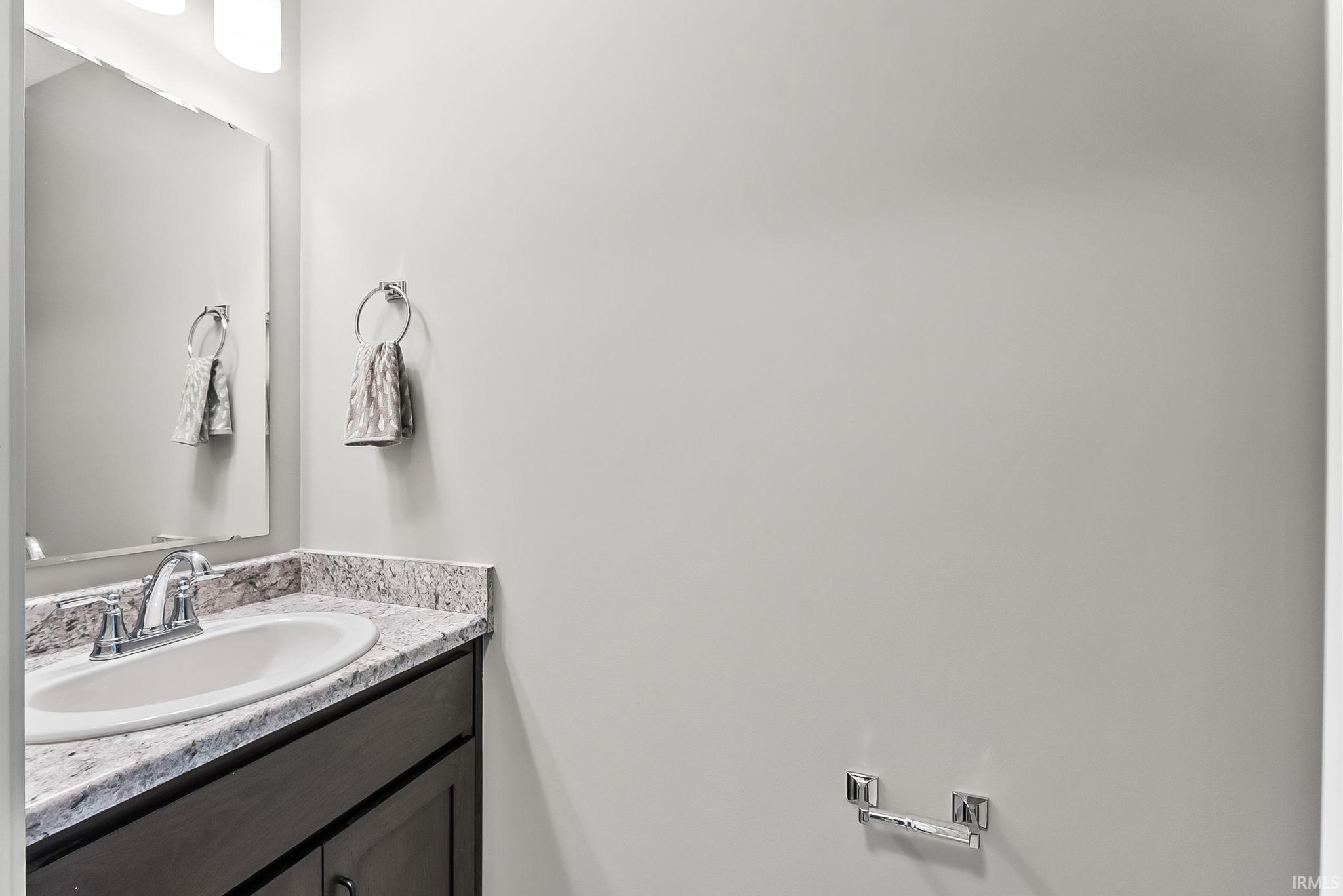 Bathroom vanity featuring a stone countertop, an undermount sink, a chrome faucet, and a dark wood-finish cabinet