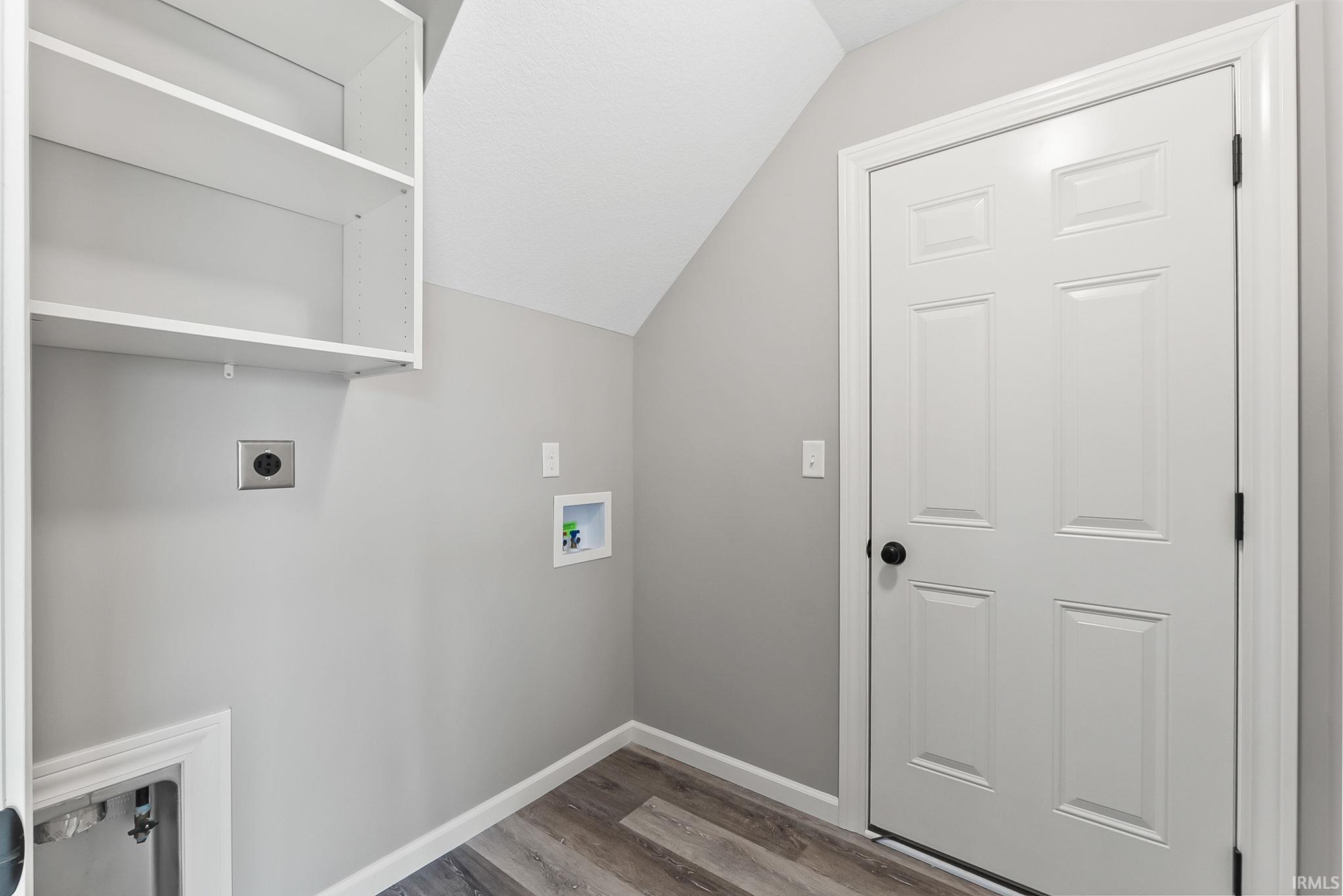 Laundry area featuring built-in shelving, light gray wall paint, and wood-finish flooring