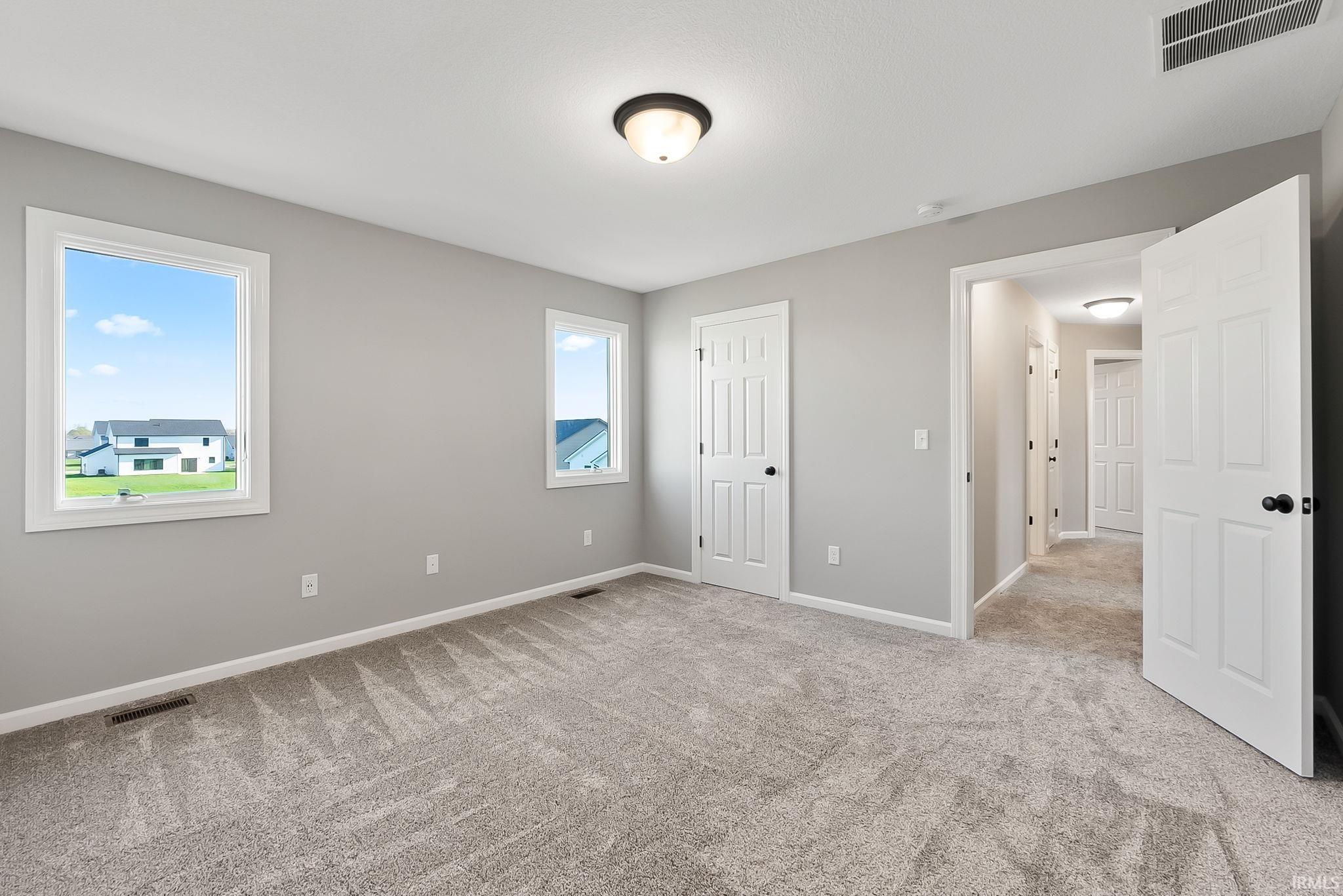 Unfurnished bedroom with light colored carpet and baseboards